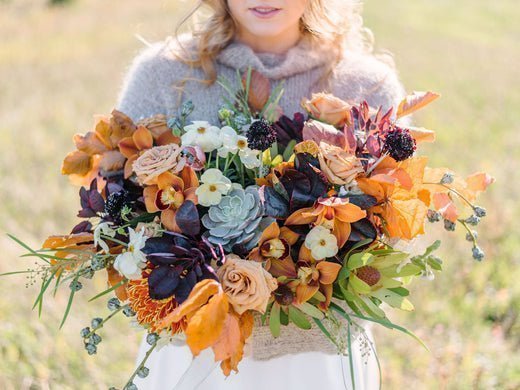 Cosy sweatered bride holding colorful flower bouquet.
