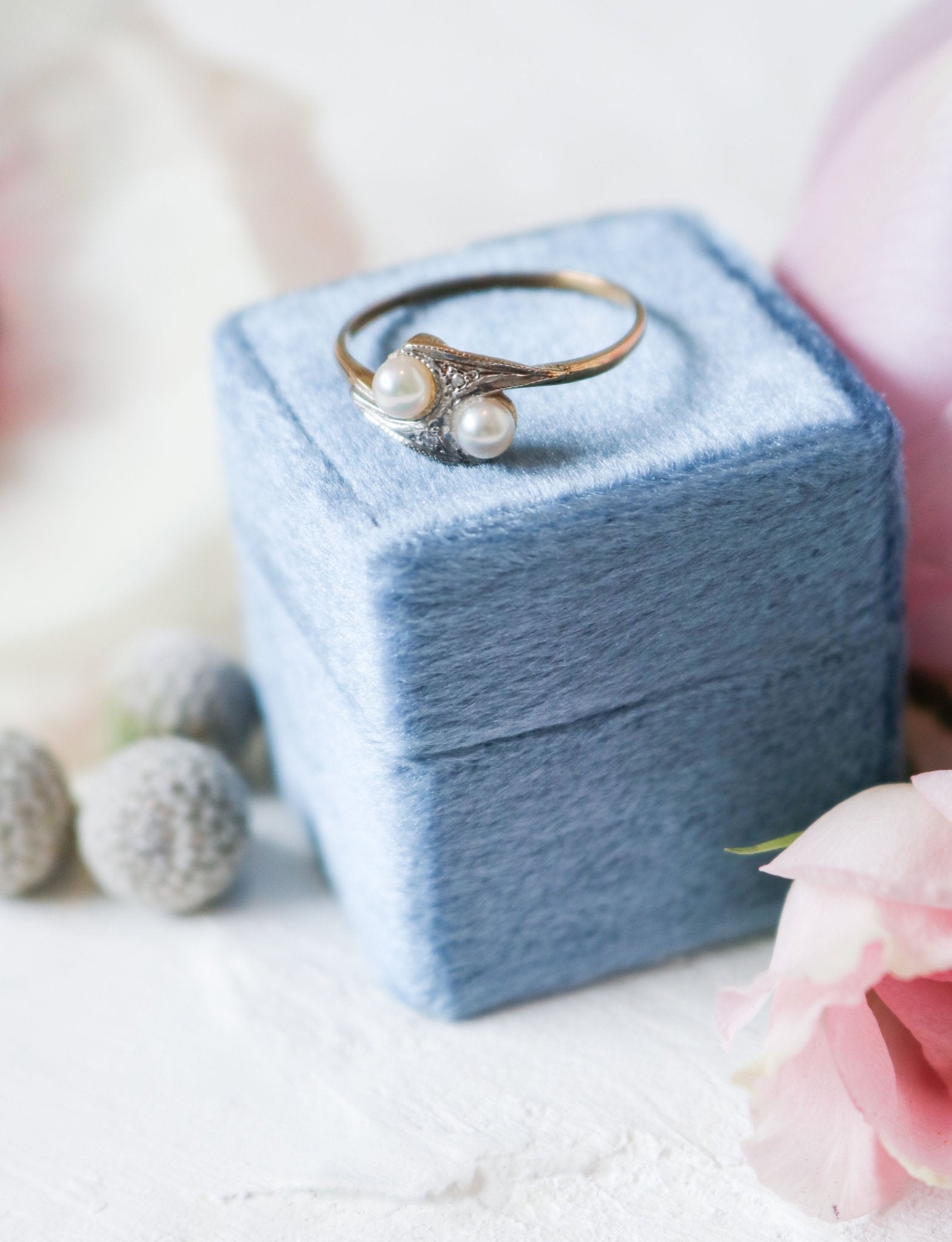A Double Pearl and Diamond Vintage Engagement Ring in 9k Yellow White Gold on top of a blue square ring box. Antique Engagement Rings Canada. Canadian vintage engagement rings. Vintage engagement rings Canada. Bridal jewelry Canada. Canadian weddings. Wedding Canada. Canadian jewelry brands. Affordable Canadian jewelry brands. Canadian bridal jewelry. Woman-owned Canadian jewelry brand. Pearl jewelry Canada. Pearl Bridal jewelry Canada. Organic pearl jewelry.