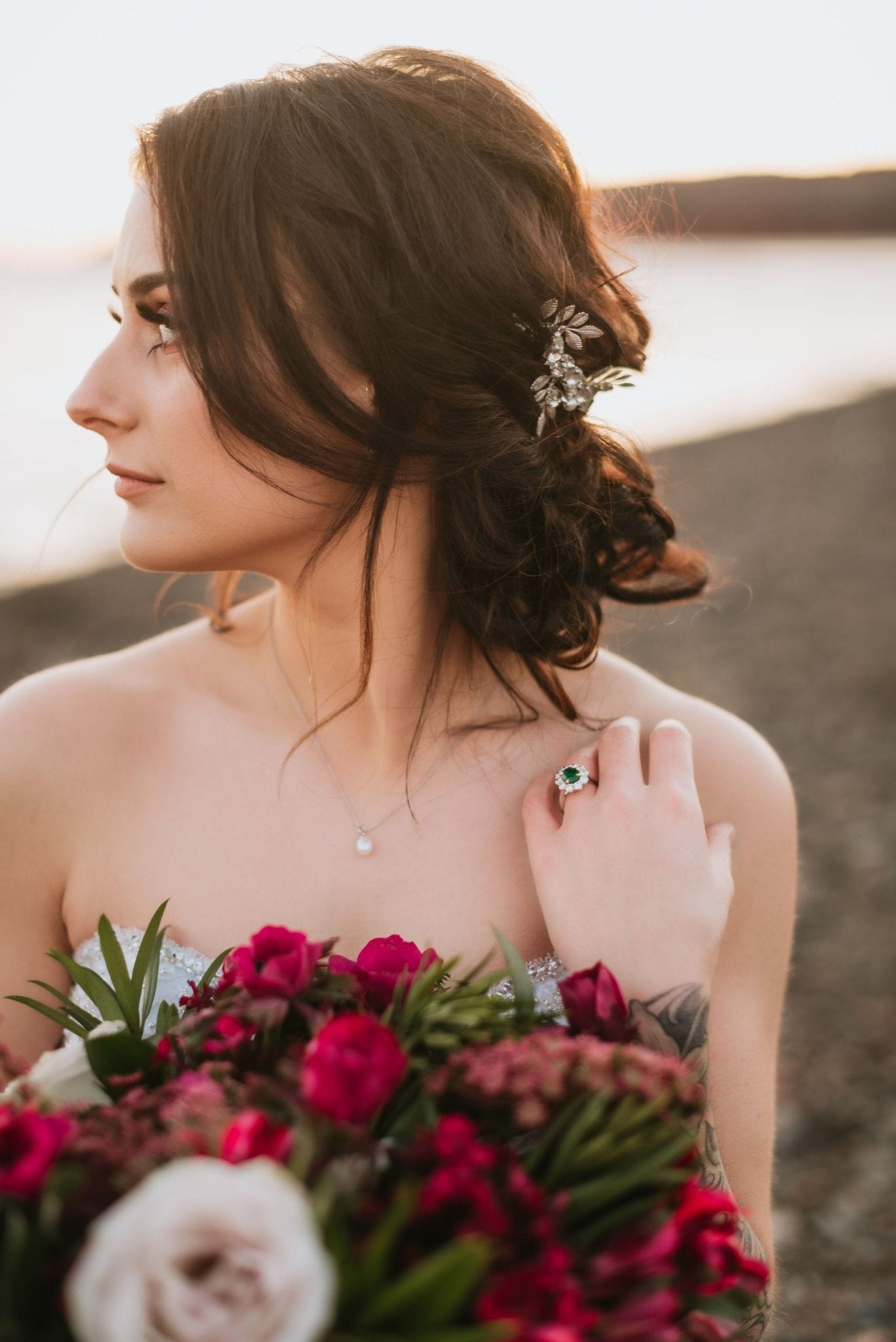 A new bride shows off her vintage ring while holding bouquet of flowers. Her hair accessory a silver bridal crown set with crystals.