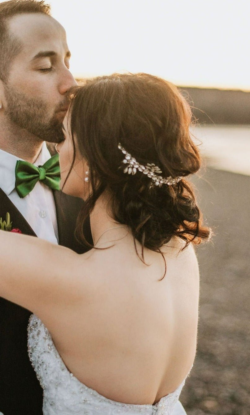 A groom kisses his bride's forehead. Her silver crystal bridal hair crown accentuates her dark curly hair with crystals. Bridal Hair Accessories. Bridal Accessories. Canadian Bridal Accessories. Handmade Canadian Accessories. Canadian handmade Accessories. Canadian weddings. Wedding Canada.