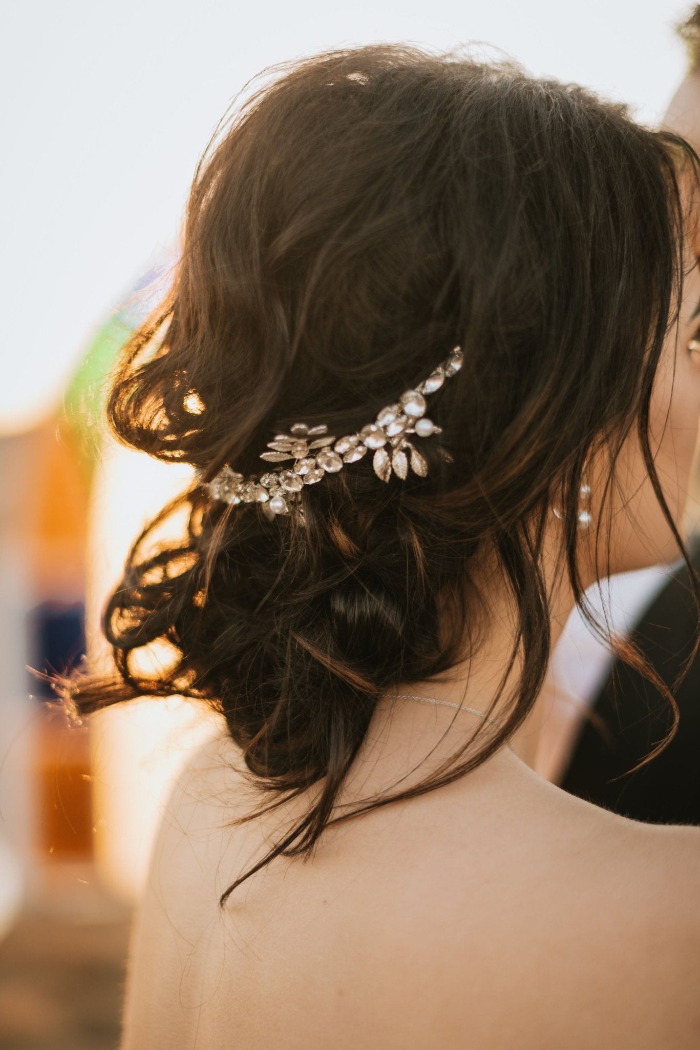 Silver Anwen Crystal & Leaf Crown Bridal Hair Accessory Sitting on Top of Curly Dark Hair Bun. Bridal Hair Accessories. Bridal Accessories. Canadian Bridal Accessories. Handmade Canadian Accessories. Canadian handmade Accessories. Canadian weddings. Wedding Canada.