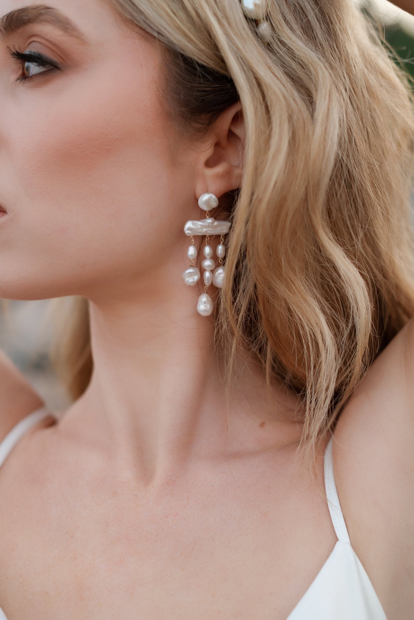 A woman with her head turned wearing chandelier earrings in gold-filled with freshwater pearls. Pearl Bridal jewelry Canada. Gold-filled jewelry Canada.