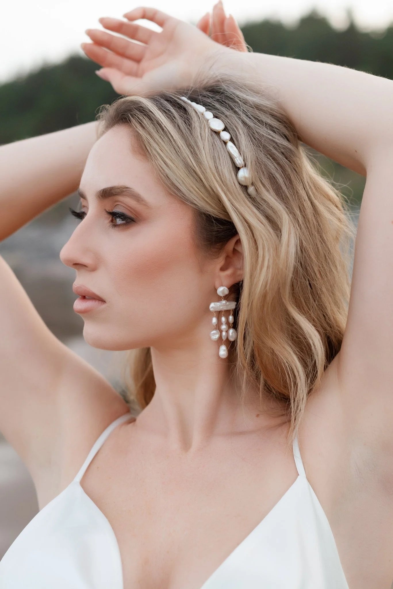 Woman with arms over head wearing gold-filled chandelier earrings with organic freshwater pearls. Pearl bridal jewelry for Canadian weddings. Pearl jewelry sets handmade by Canadian jewelry designer