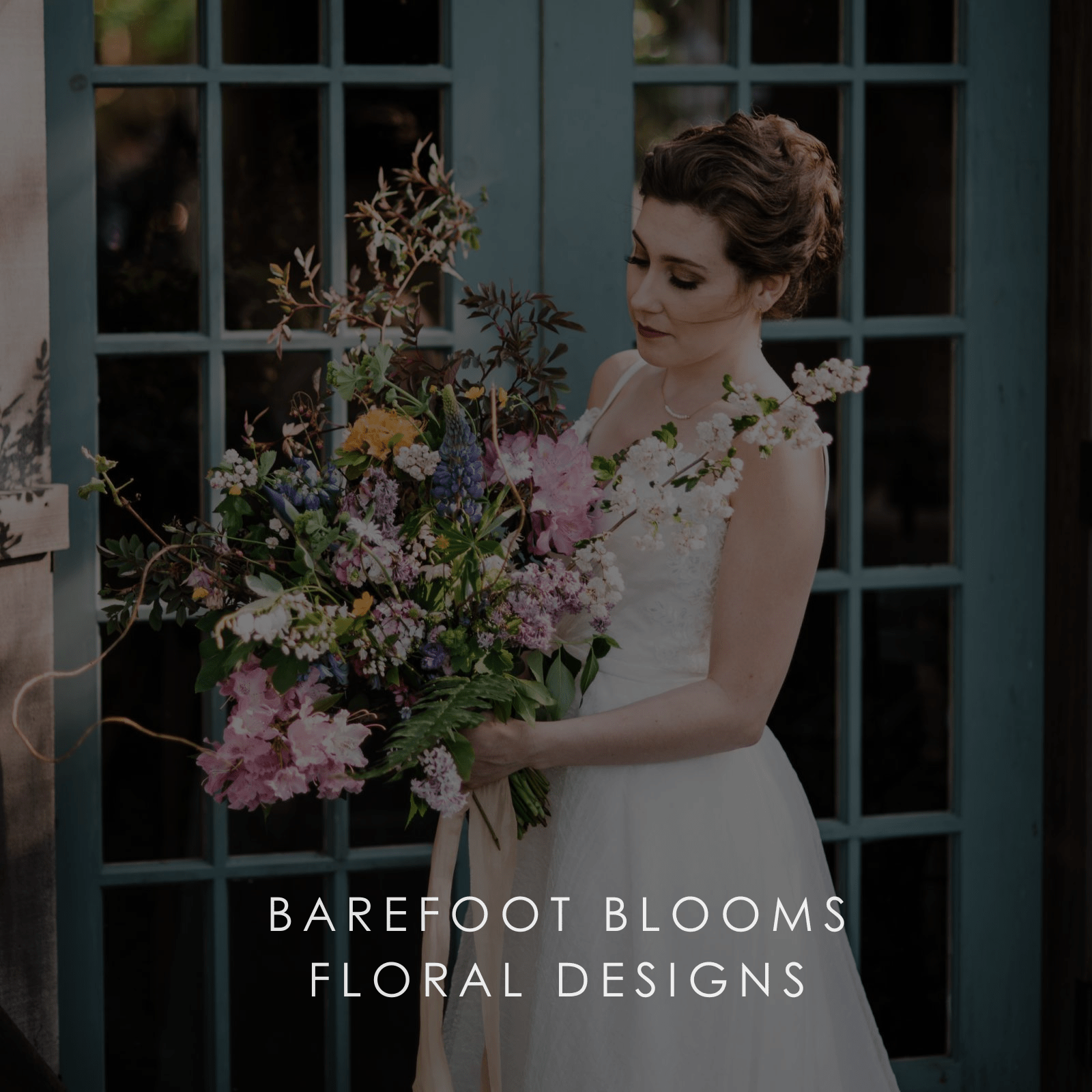 A bride in a white wedding gown holds a large bridal bouquet of assorted flowers.