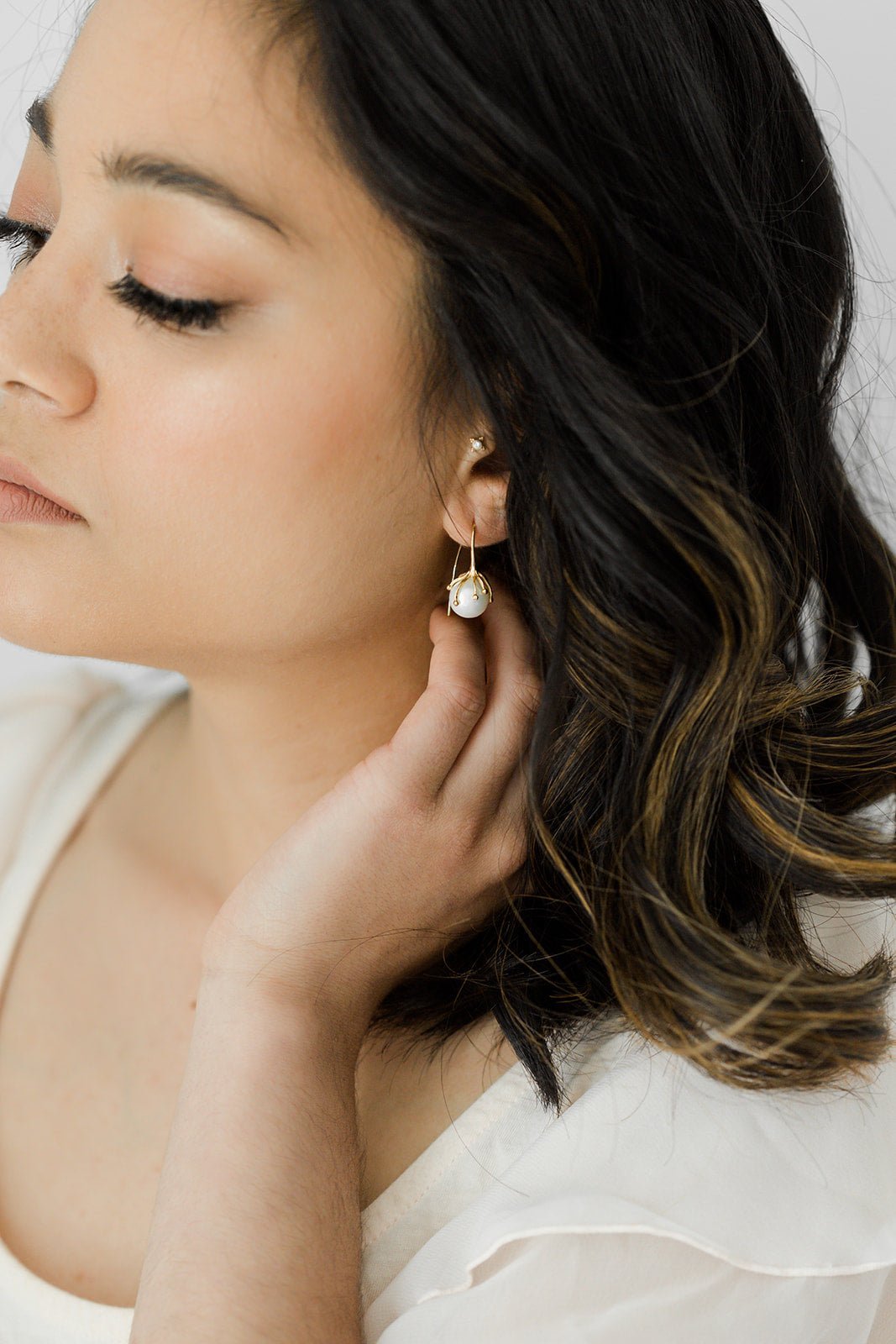 A Bloom Flower Bud Freshwater Pearl Earring hangs from a woman's ear. Pearl jewelry Canada. Pearl Bridal jewelry Canada. Gold-filled jewelry Canada. Organic Pearl Jewelry. Handmade jewelry Canada.