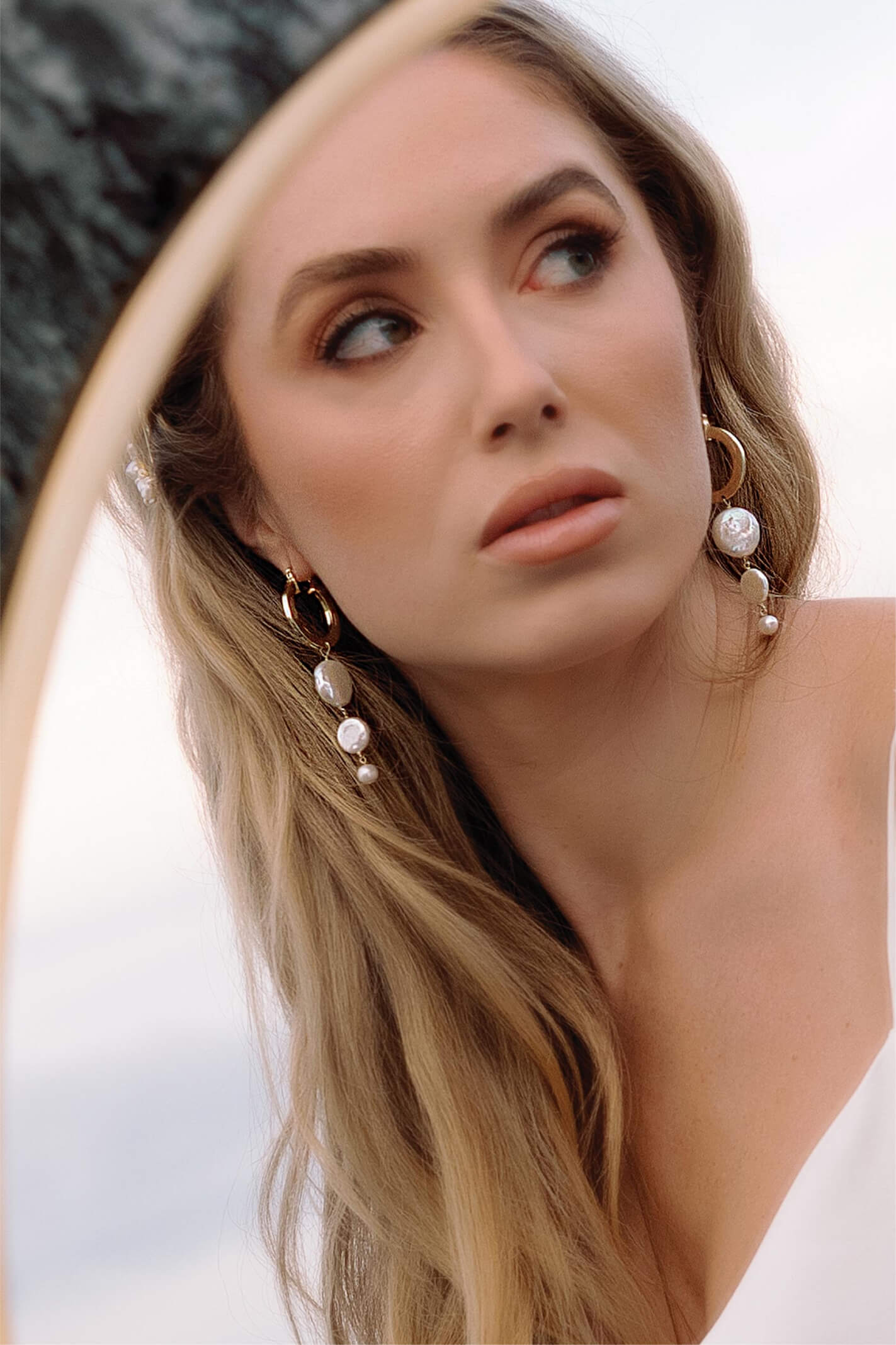 Beautiful bride in a mirror wearing gold-filled hoops dangling freshwater coin pearls.