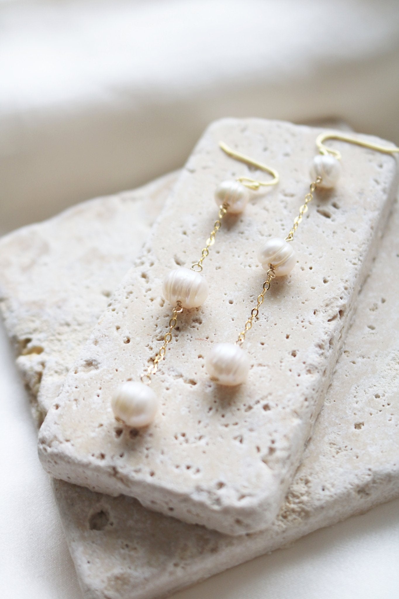 A pair of gold-filled bubble freshwater pearls are displayed on flat pieces of stone. Organic pearl jewelry. Bridal jewelry Canada. Pearl jewelry Canada. Pearl Bridal jewelry Canada. Gold-filled jewelry Canada. Canadian weddings. Affordable Canadian jewelry brands. Handmade Canadian jewelry. Canadian jewelry maker. Canadian bridal jewelry.