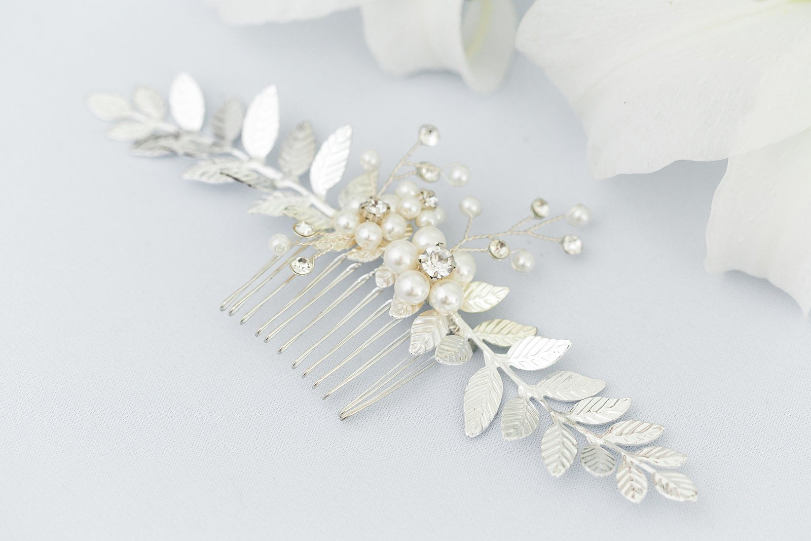 Close up of a silver pearl and crystal bridal hair comb with leaves on a white background. Canadian bridal accessories, bridal hair accessories, & handmade Canadian accessories by a Canadian bridal designer
