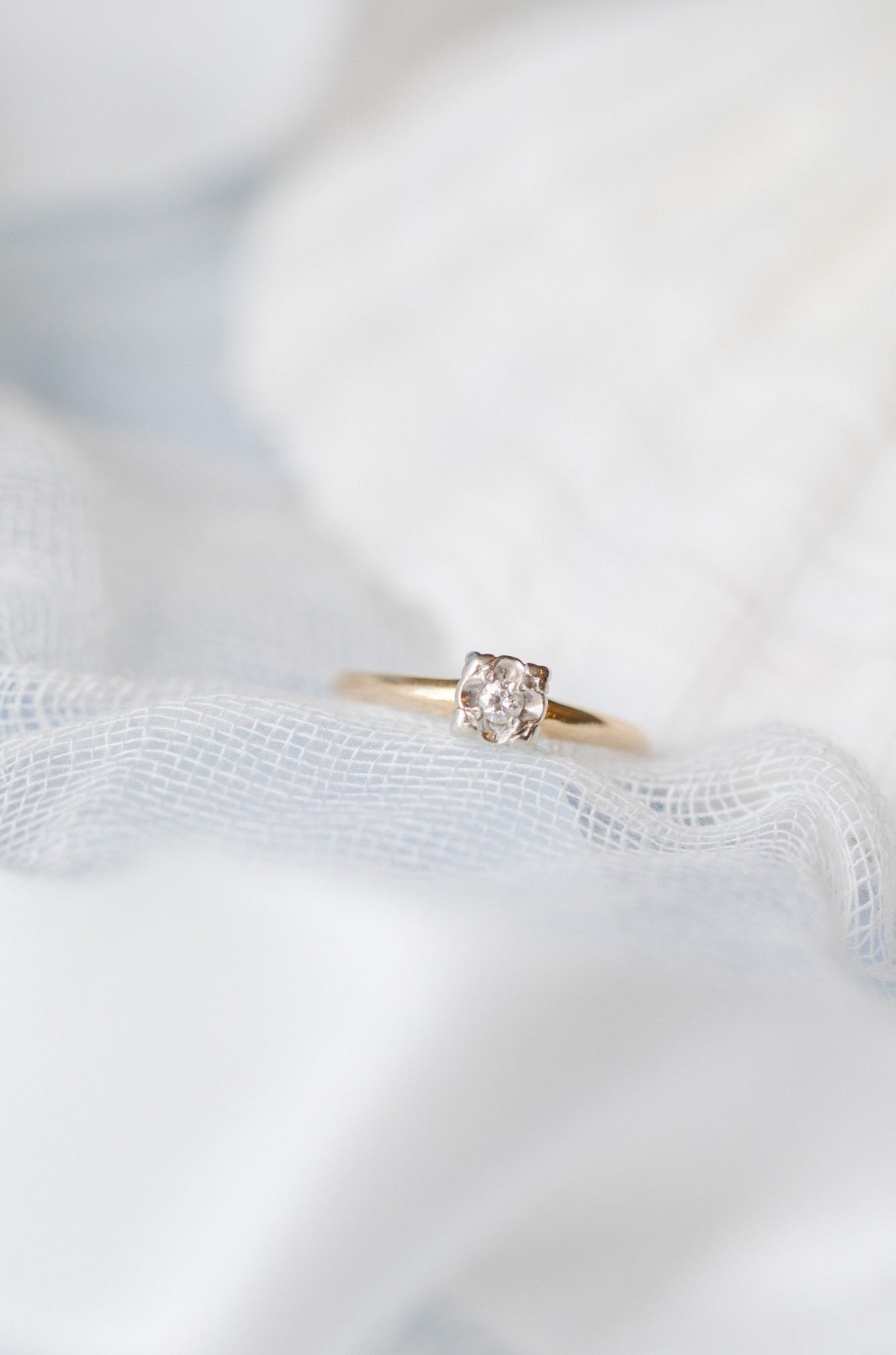 A diamond and gold vintage engagement ring sits on a white fabric surface. Antique Engagement Rings Canada. Canadian vintage engagement rings. Vintage engagement rings Canada. Bridal jewelry Canada. Canadian weddings. Wedding Canada. Canadian bridal jewelry. Woman-owned Canadian jewelry brand. Canadian jewelry business.
