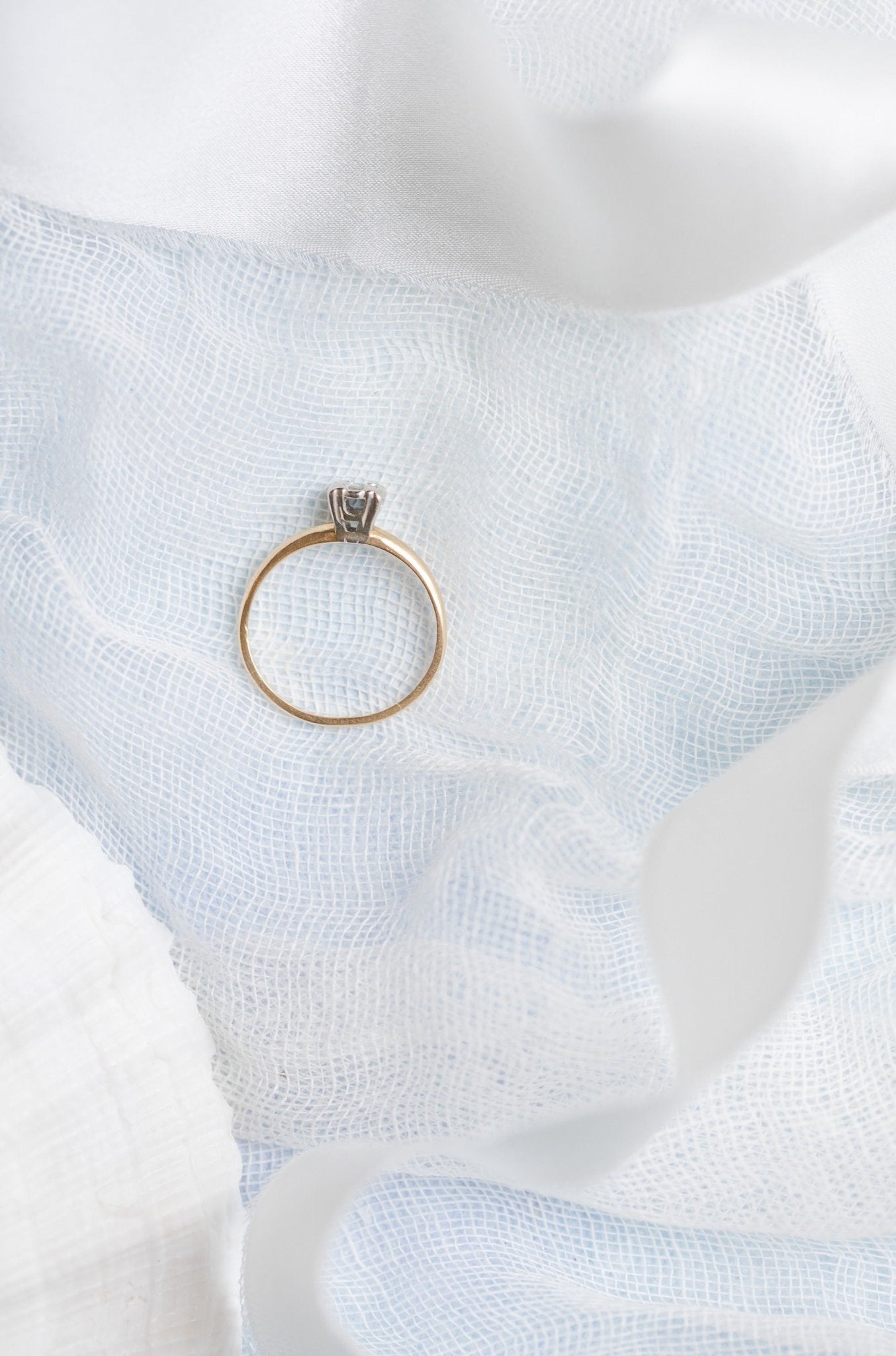The top view of a diamond and gold vintage engagement ring sits on a white fabric surface. Antique Engagement Rings Canada. Canadian vintage engagement rings. Vintage engagement rings Canada. Bridal jewelry Canada. Canadian weddings. Wedding Canada. Canadian bridal jewelry. Woman-owned Canadian jewelry brand. Canadian jewelry business.