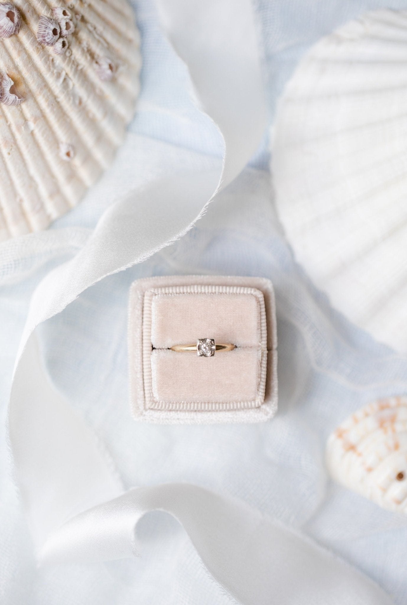 A top view of a 14k Yellow and White Gold Vintage Diamond Engagement Ring sitting in a ring box on a white backdrop with seashells. Antique Engagement Rings Canada. Canadian vintage engagement rings. Vintage engagement rings Canada. Bridal jewelry Canada. Canadian weddings. Wedding Canada. Canadian bridal jewelry. Woman-owned Canadian jewelry brand. Canadian jewelry business.