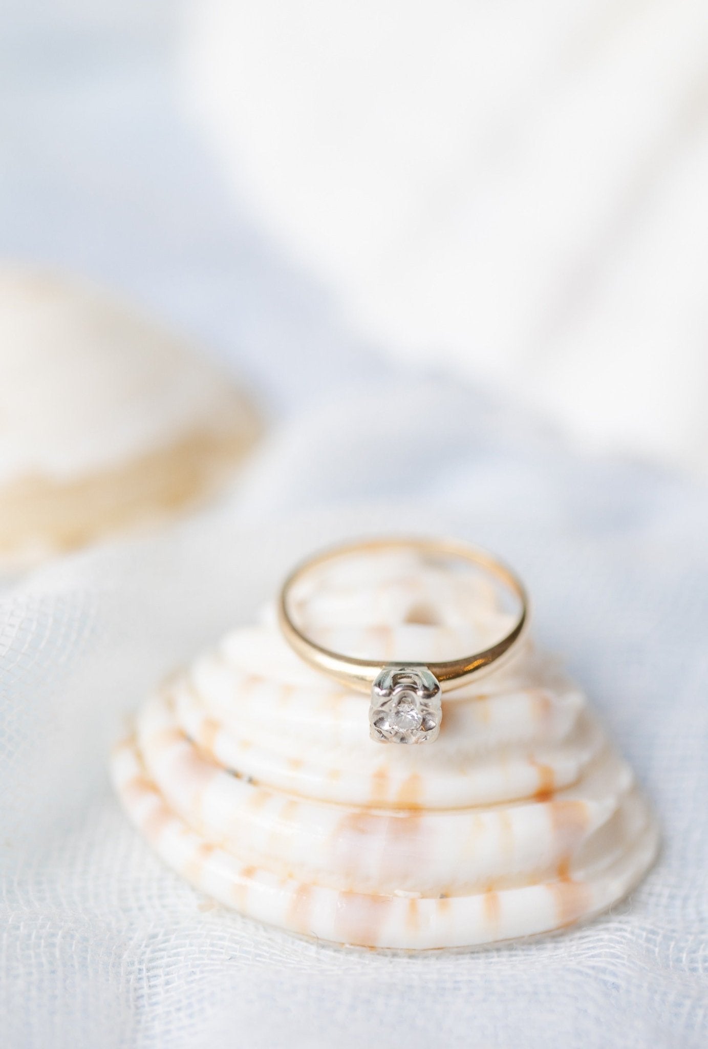 The Claire Vintage Diamond Solitaire Engagement Ring in 14k Yellow and White Gold sits on top of a shell against a white background. Antique Engagement Rings Canada. Canadian vintage engagement rings. Vintage engagement rings Canada. Bridal jewelry Canada. Canadian weddings. Wedding Canada. Canadian bridal jewelry. Woman-owned Canadian jewelry brand. Canadian jewelry business.