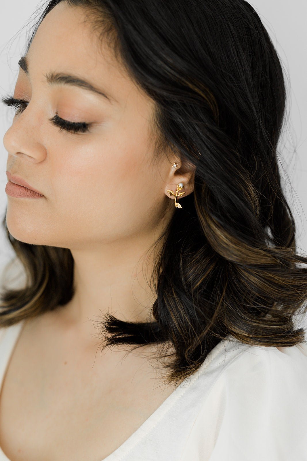 Gold-filled freshwater pearl floral earring on woman's ear. Affordable bridal jewelry & pearl bridal jewelry handmade by Canadian jewelry business