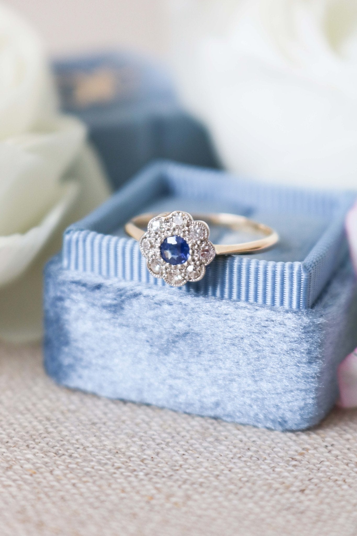 A close up front view of a 18k Yellow and White Gold Vintage Sapphire and Diamond Engagement Ring on top of a powder blue ring box. Canadian vintage engagement rings. Bridal jewelry Canada. Canadian weddings. Wedding Canada. Canadian bridal jewelry. Woman-owned Canadian jewelry brand. Canadian jewelry brands.