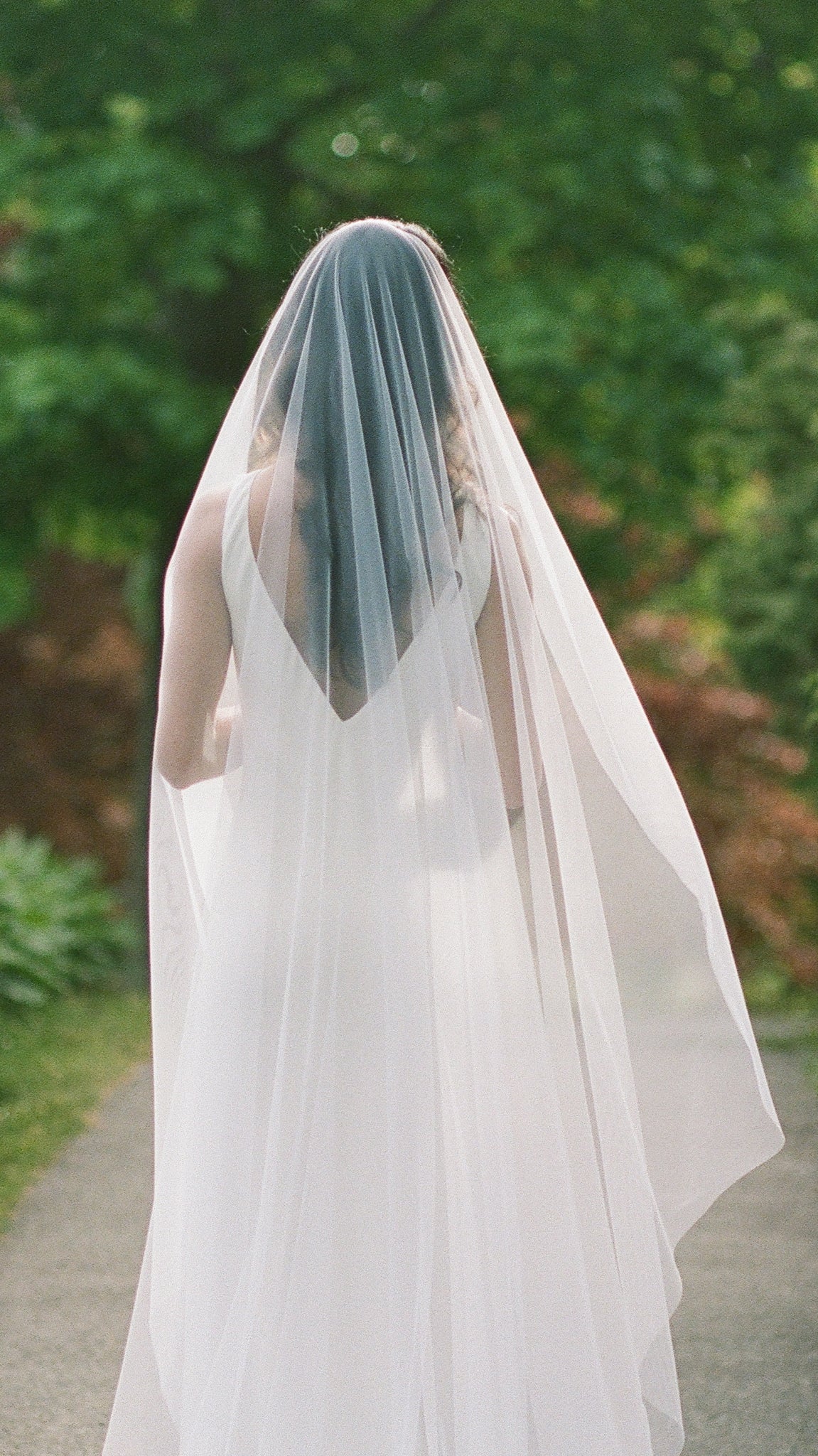 The back of a bride shrouded in a soft tulle wedding veil. Canadian weddings. Wedding Canada. Wedding veils Canada. Bridal Hair Accessories. Bridal Accessories. Canadian Bridal Accessories. Handmade Canadian Accessories. Canadian handmade Accessories. Canadian designer. Canadian artist.