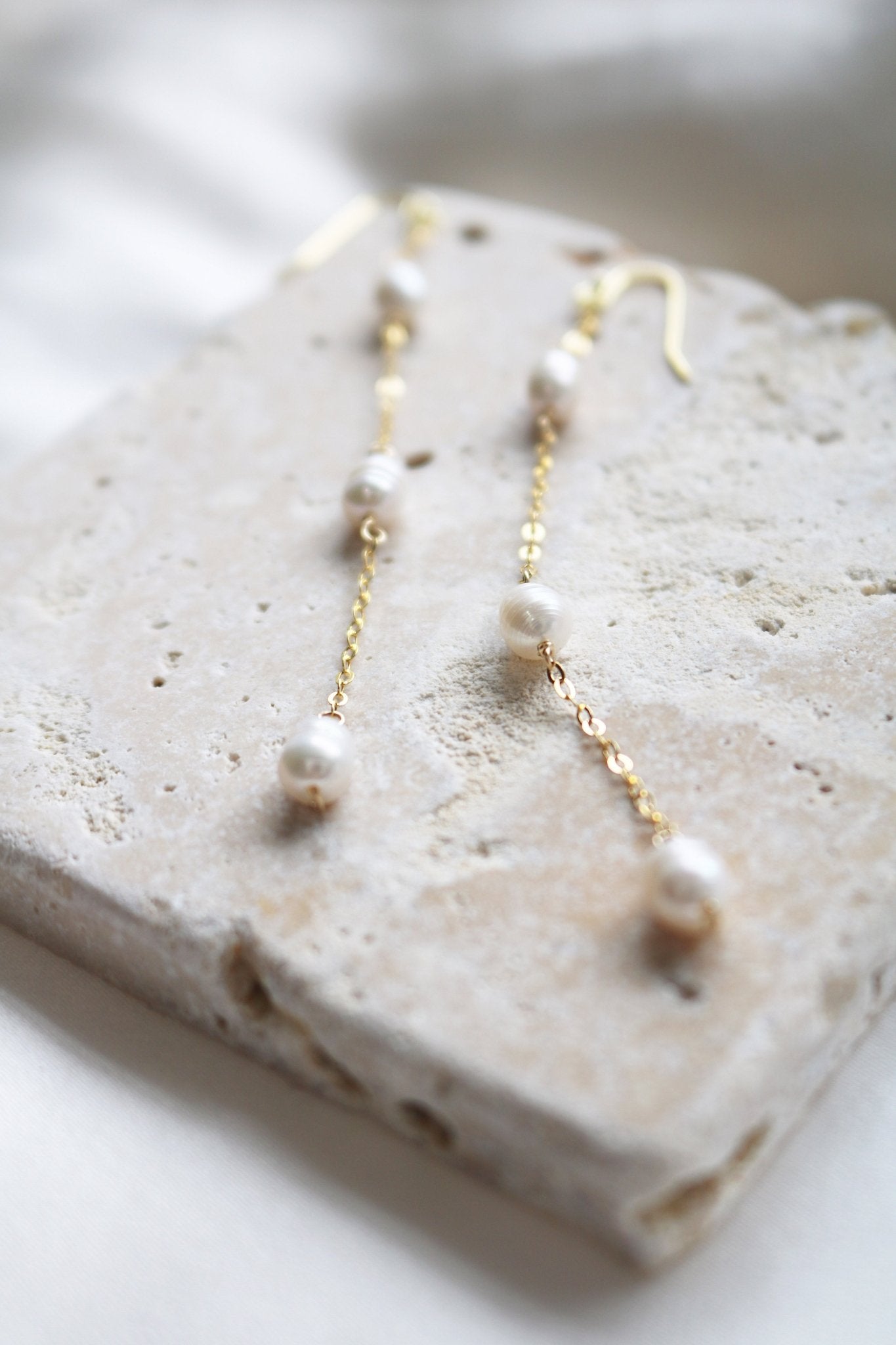 A pair of golden pearl earrings set on stone. Organic pearl jewelry. Bridal jewelry Canada. Pearl jewelry Canada. Pearl Bridal jewelry Canada. Gold-filled jewelry Canada. Canadian weddings. Affordable Canadian jewelry brands. Handmade Canadian jewelry.