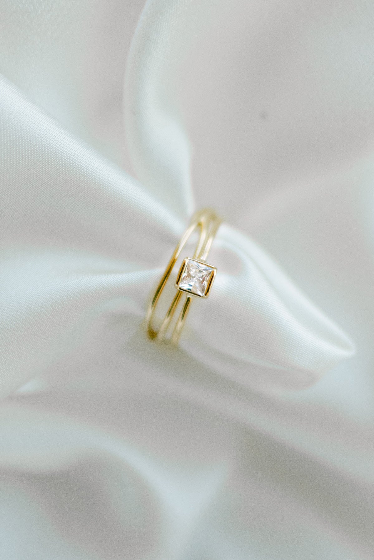 Two gold-filled rings on a white satin fabric; one with square cubic zirconia crystal. Affordable jewelry. Handmade Canadian jewelry. Canadian jewelry maker.