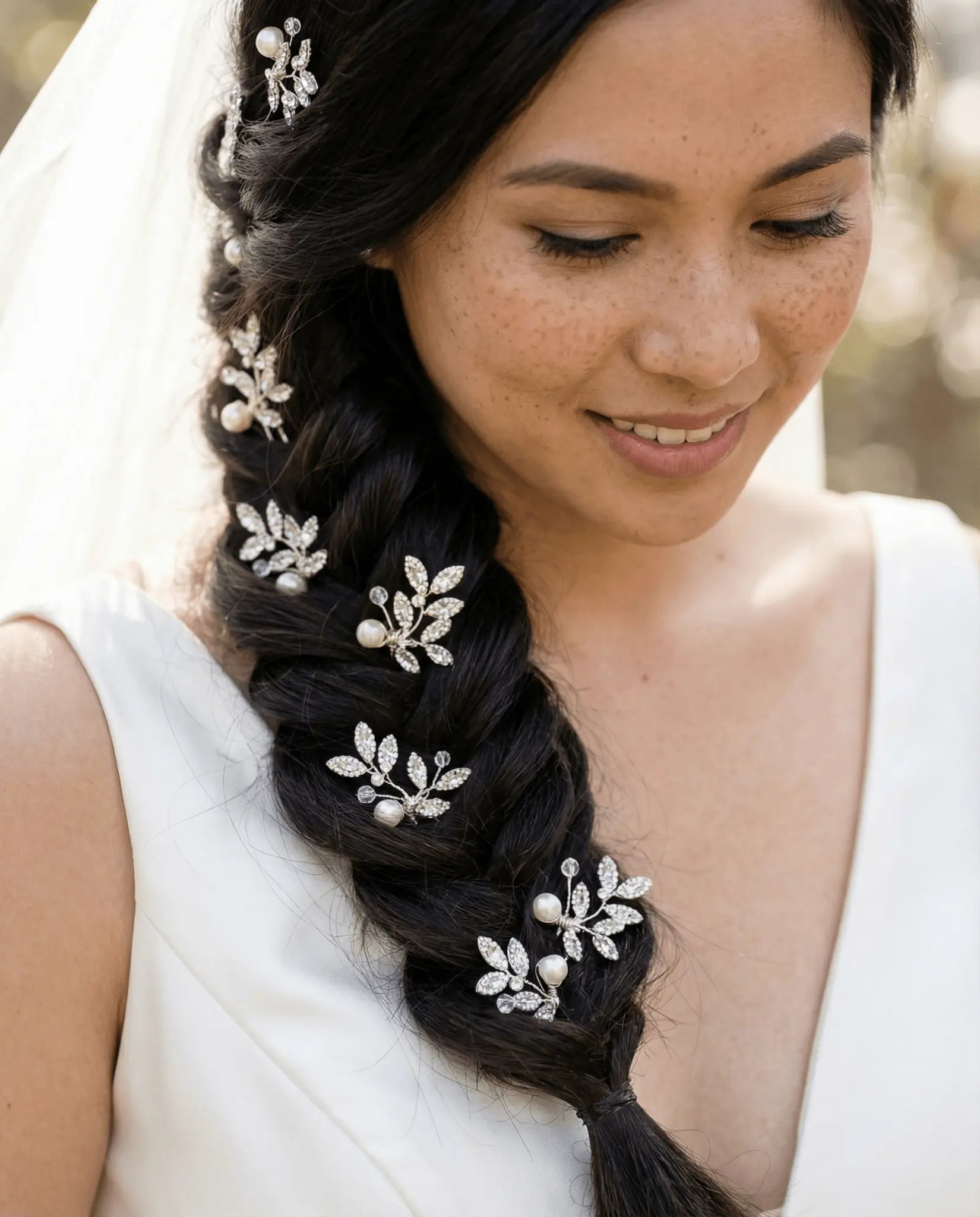 Filipino woman with dark braided hair adorned with Swarovski crystal and freshwater pearl decorative bridal hairpins against a neutral background. Handmade bridal hair accessories by woman-owned Canadian business.