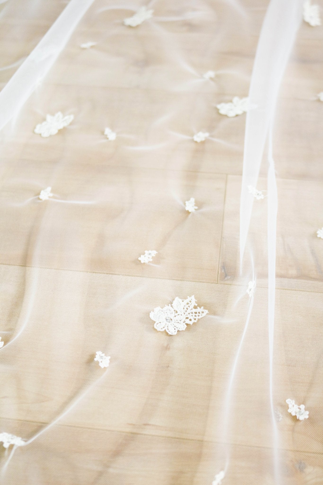 A close up of the detailed embroidered flowers on a wedding veil spread across a wooden floor. Canadian weddings. Wedding Canada. Wedding veils Canada. Bridal Hair Accessories. Bridal Accessories. Canadian Bridal Accessories. Handmade Canadian Accessories. Canadian handmade Accessories. Canadian designer. Canadian artist.