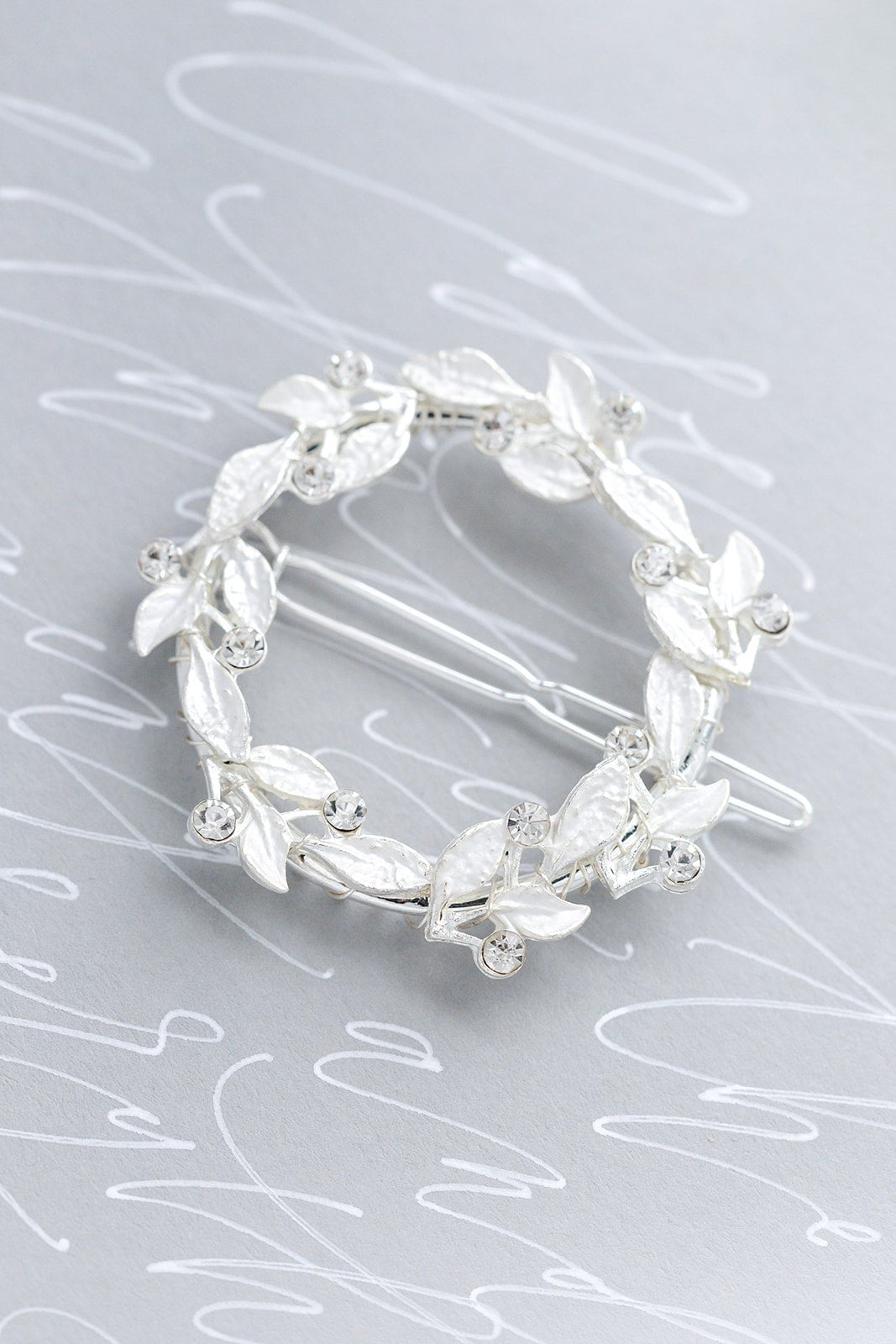 Full silver crystal wreath bridal hair barrette on a grey surface with white cursive writing. Bridal hair accessories & Handmade Canadian accessories good for everyday wear & weddings by Canadian jewelry brand