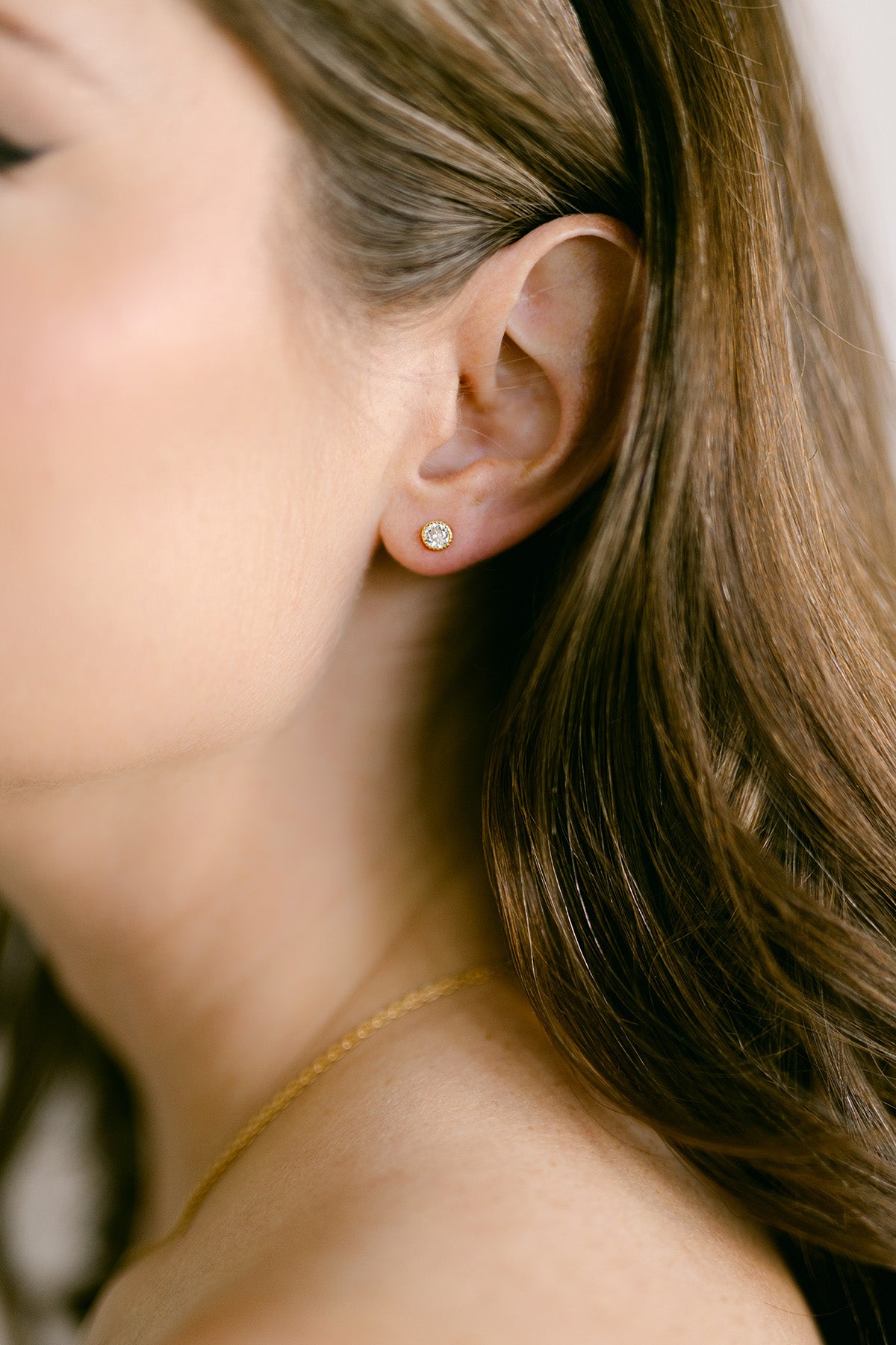 Close-up of a person wearing a gold-filled stud earring with large crystal. Woman-owned business. Canadian jewelry business. Affordable jewelry.