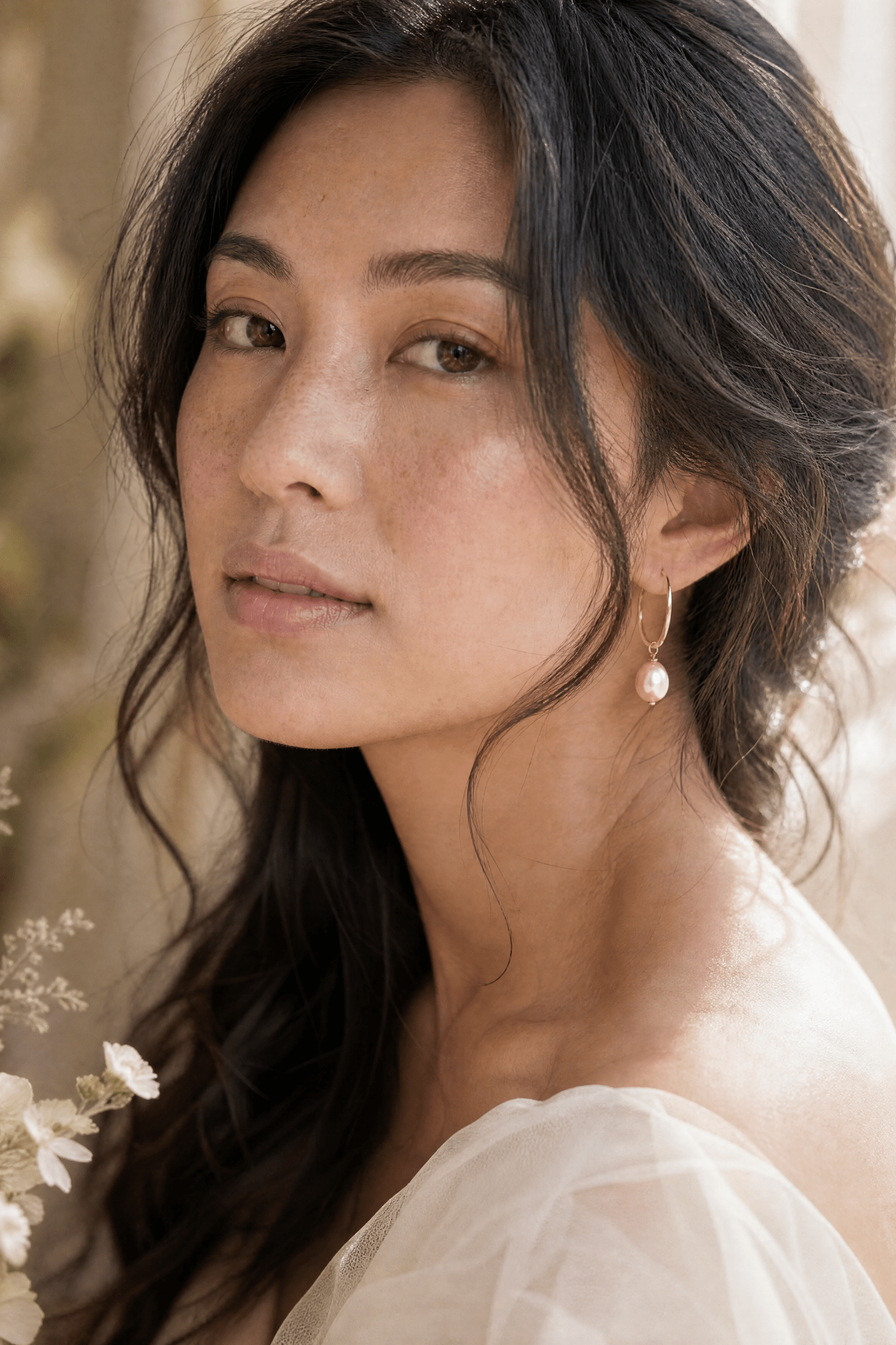 BIPOC model with long dark hair wearing a gold filled hoop earring with blush fresh water pearl. Handmade gold earrings by Canadian BIPOC designer