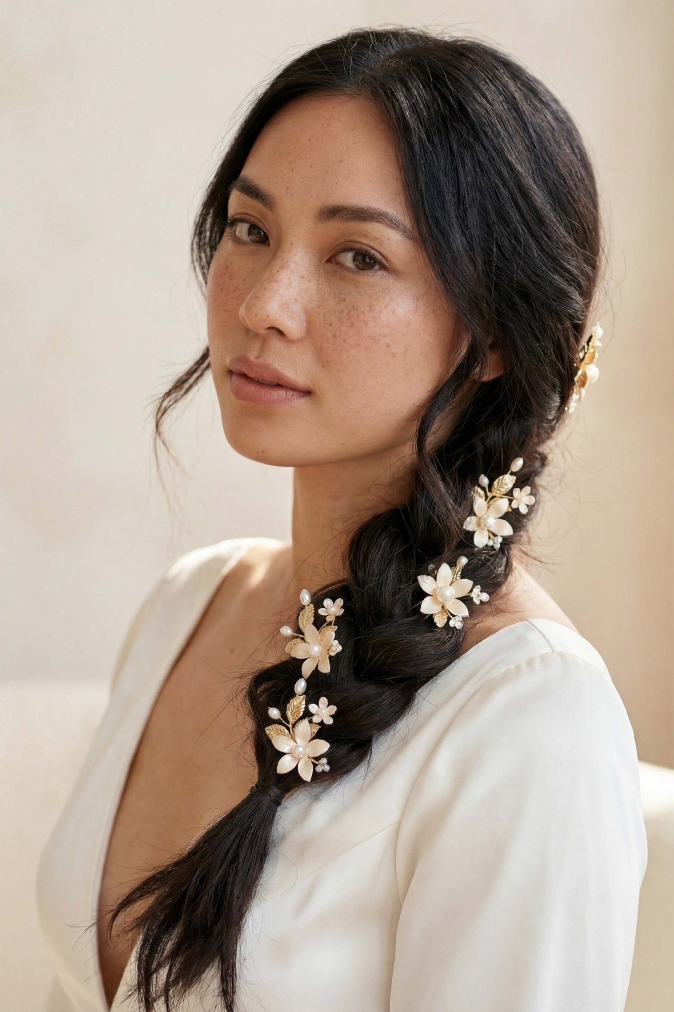 Filipina bride with braided hair adorned with floral bridal hairpins against a neutral background. Handmade Canadian bridal accessories and Pearl Bridal Hair Accessories by woman-owned jewelry brand.