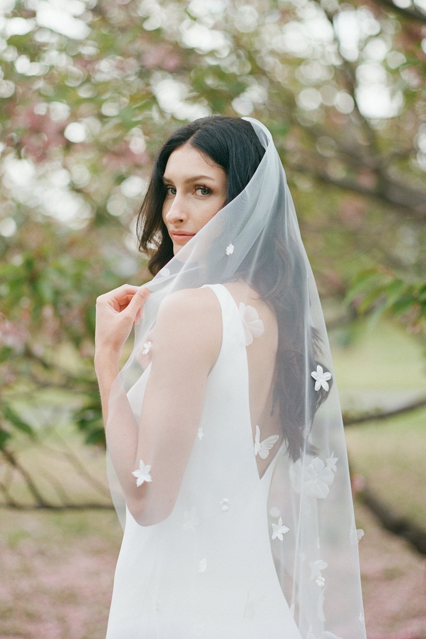 A coy bride hides some of her face with her flower blossom embroidered veil. Canadian weddings. Wedding Canada. Wedding veils Canada. Bridal Hair Accessories. Bridal Accessories. Canadian Bridal Accessories. Handmade Canadian Accessories. Canadian handmade Accessories. Canadian designer. Canadian artist.