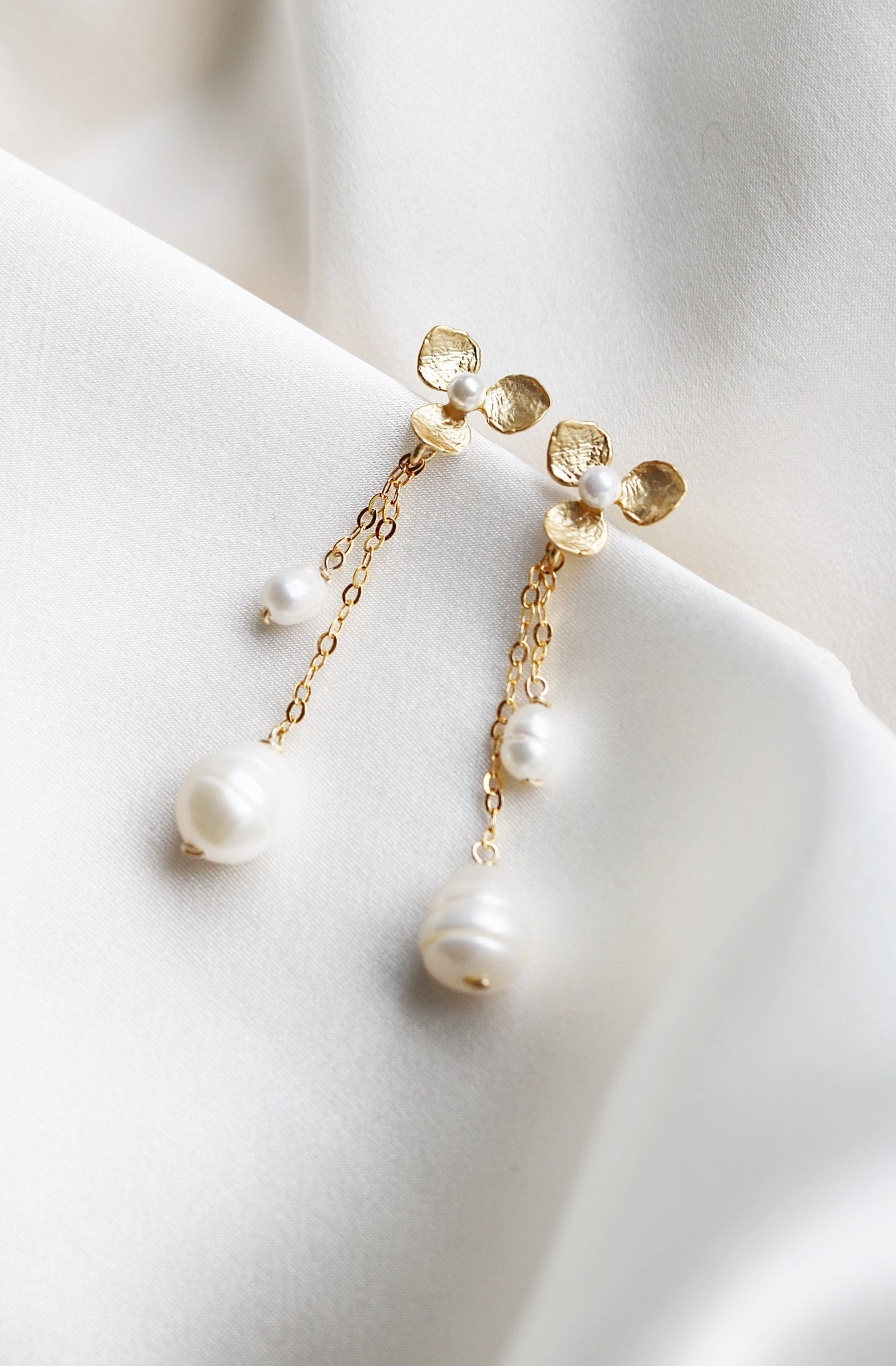 Gold Filled Flor De Amor Earrings lay on a white cloth, displaying their blossoms and pearls. Bridal jewelry Canada. Pearl jewelry Canada. Pearl Bridal jewelry Canada. Gold-filled jewelry Canada. Handmade Canadian jewelry. Organic pearl jewelry.