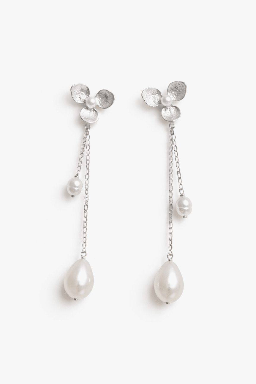 Pair of floral designed fresh water pearl earrings with dangle chains on a white background. Pearl bridal jewelry & handmade bridal earrings by affordable Canadian jewelry brand