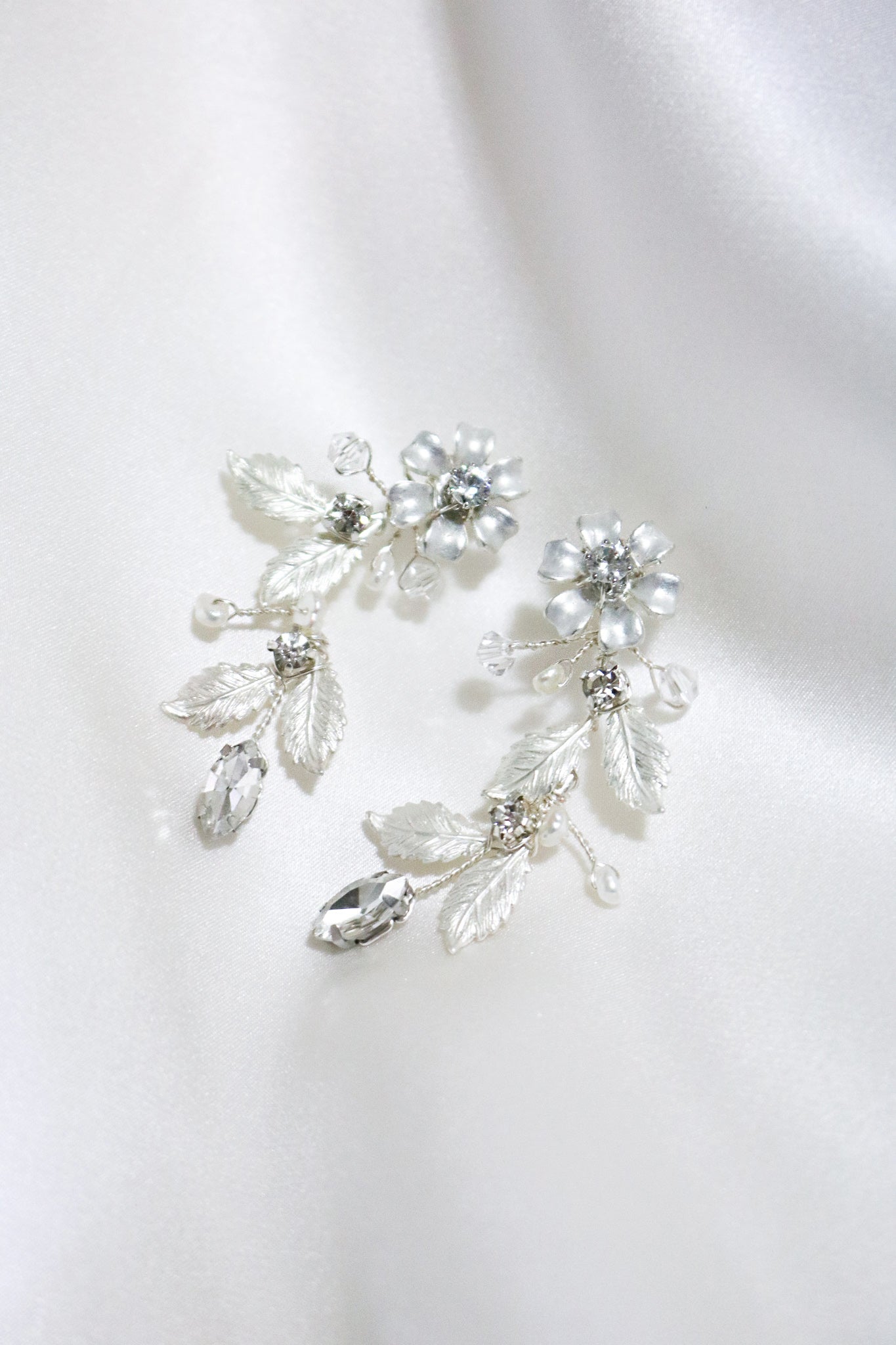 A pair of Silver Floriana Flower and Foliage Earrings on a white satin sheet. Bridal jewelry Canada. Sterling Silver jewelry Canada. Canadian jewelry brands. Affordable Canadian jewelry brands. Handmade Canadian jewelry. Canadian handmade jewelry. Canadian bridal jewelry. Statement Earrings. Statement Bridal Earrings. Canadian jewelry business.