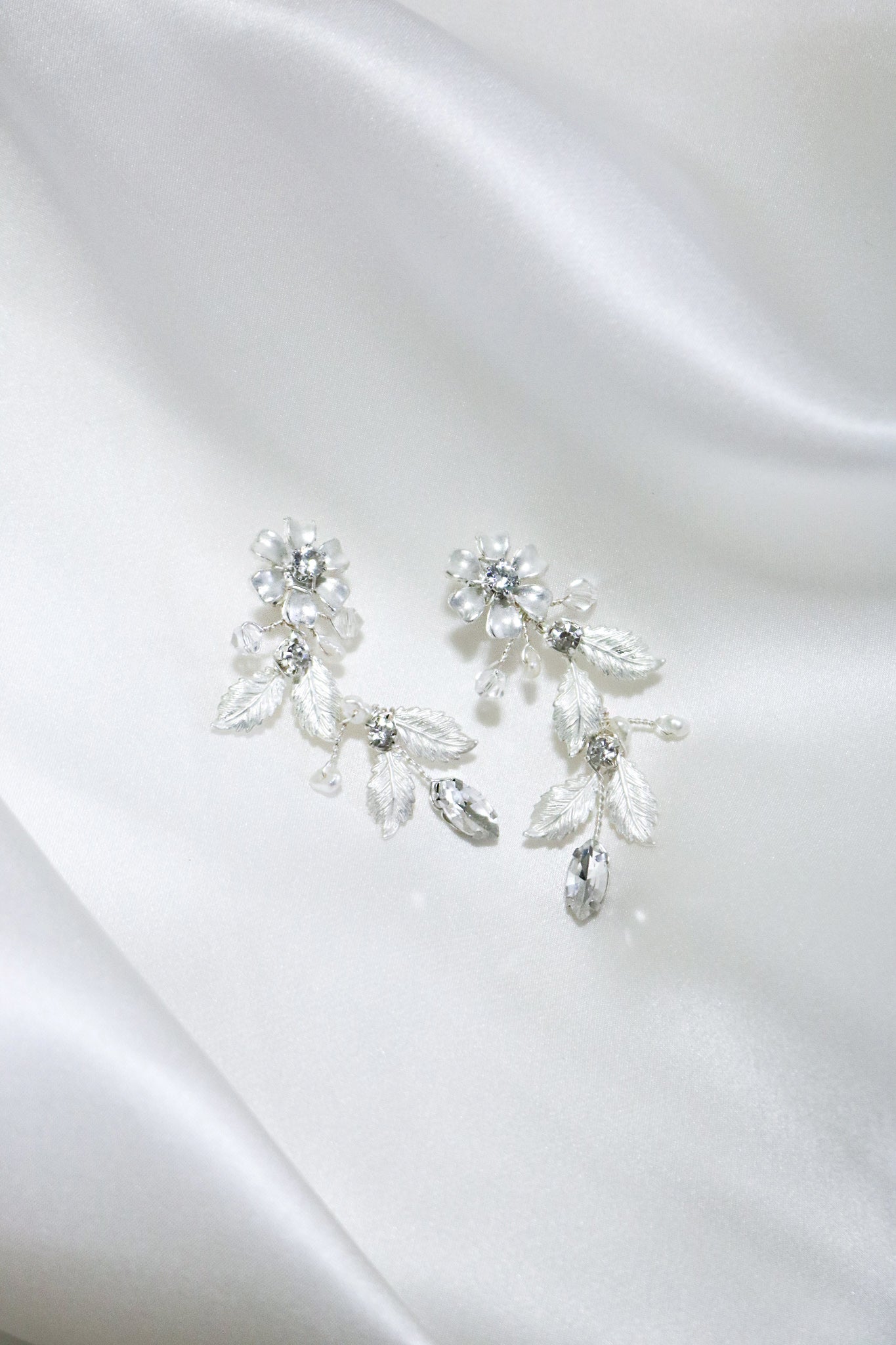 A pair of Silver Floriana Flower and Foliage Earrings on a white satin sheet. Bridal jewelry Canada. Sterling Silver jewelry Canada. Canadian jewelry brands. Affordable Canadian jewelry brands. Handmade Canadian jewelry. Canadian handmade jewelry. Canadian bridal jewelry. Statement Earrings. Statement Bridal Earrings. Canadian jewelry business.