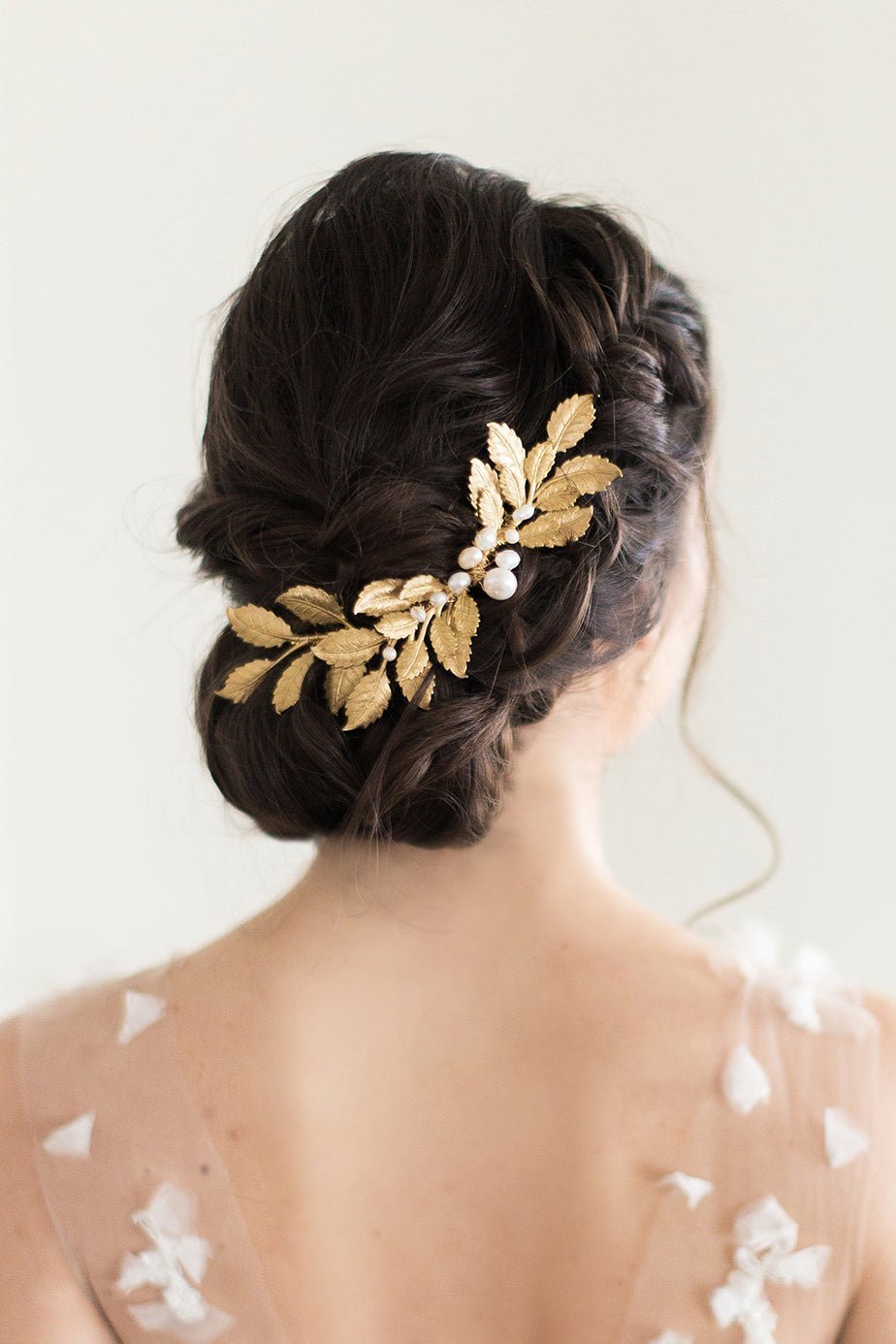 The back of a bride's head with a long golden leafed bridal haircomb with pearls tucked into a dark haired bridal up-do. Canadian bridal accessories & Handmade bridal accessories by Canadian wedding designer