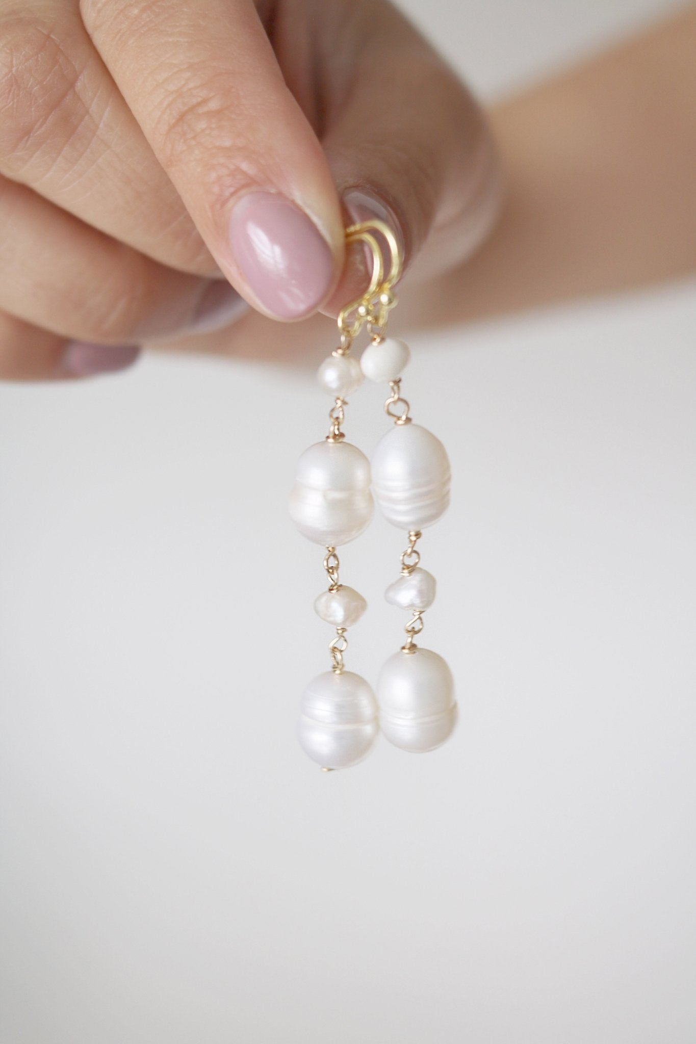 Fingers daintily hold freshwater pearl earrings with variously sized pearls. Organic pearl jewelry. Bridal jewelry Canada. Pearl jewelry Canada. Pearl Bridal jewelry Canada. Gold-filled jewelry Canada. Canadian jewelry brands. Canadian jewelry designs. Handmade Canadian jewelry.