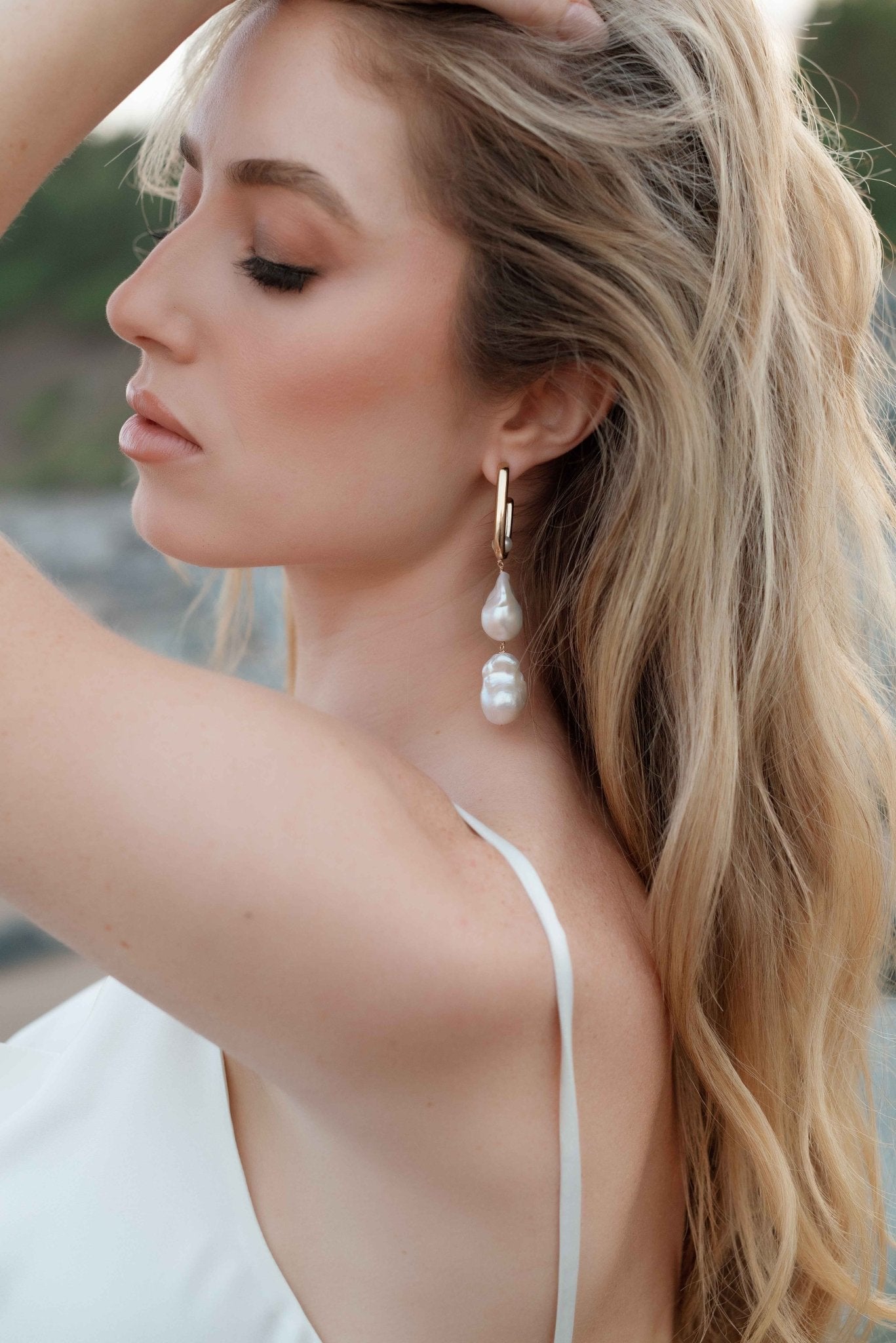 Whimsical bride poses to show off her gold-filled baroque freshwater pearl bridal earrings. Pearl Bridal jewelry Canada. Gold-filled jewelry Canada.
