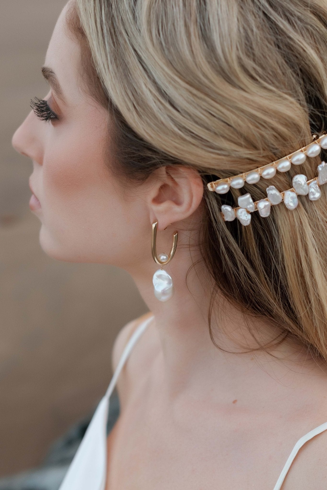 An elegant bride looks on while wearing small baroque freshwater pearl bridal earrings and gold pearl barrettes. Handmade jewelry Canada. Pearl jewelry Canada. Canadian jewelry business. Organic pearl jewelry. Bridal jewelry Canada. Pearl Bridal jewelry Canada. Gold-filled jewelry Canada. Canadian weddings. Wedding Canada. Statement Earrings. Statement Bridal Earrings.