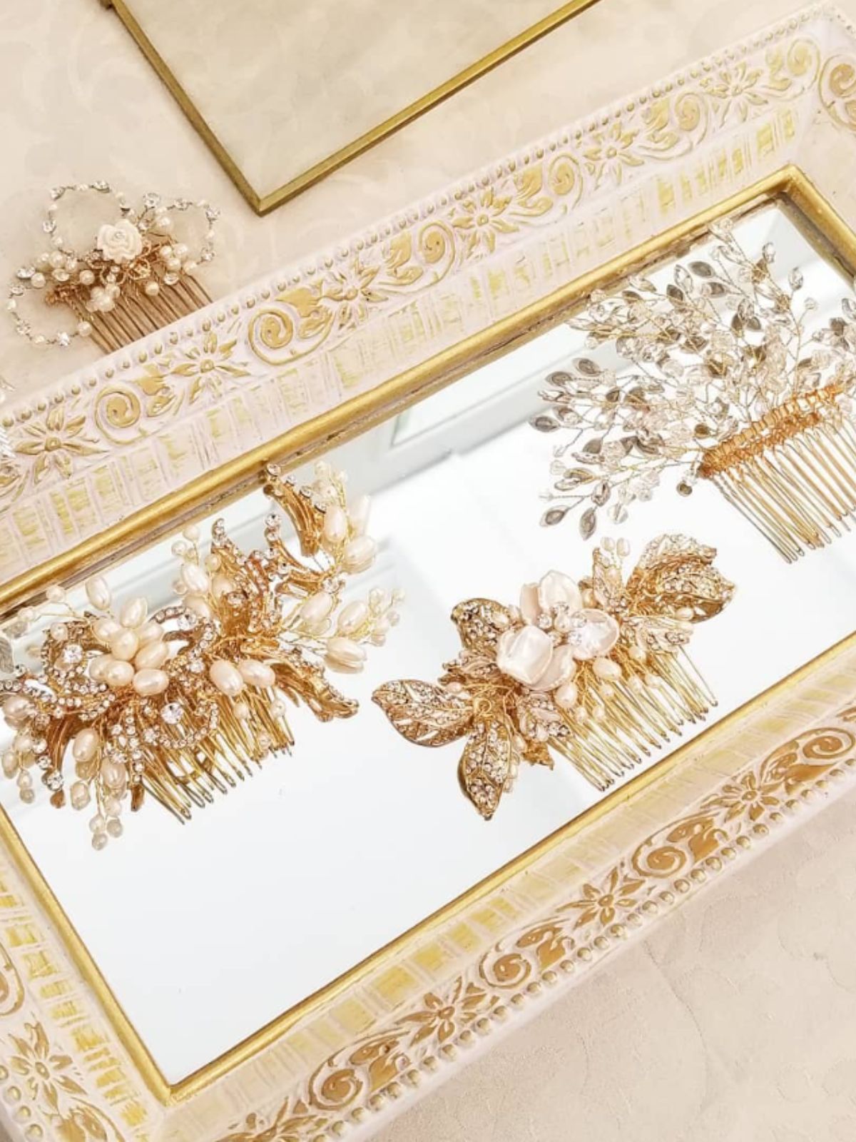 Gold decorative bridal hair combs with freshwater pearls and crystals sitting in a mirrored display tray on neutral background. Bridal hair accessories & pearl accessories Canada