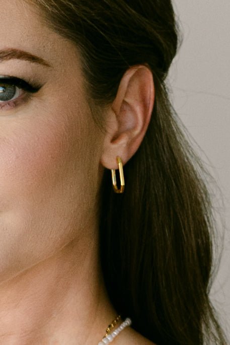 Close-up of a woman wearing square shaped gold-filled hoop earrings. Minimalist Jewelry. Everyday jewelry Canada.
