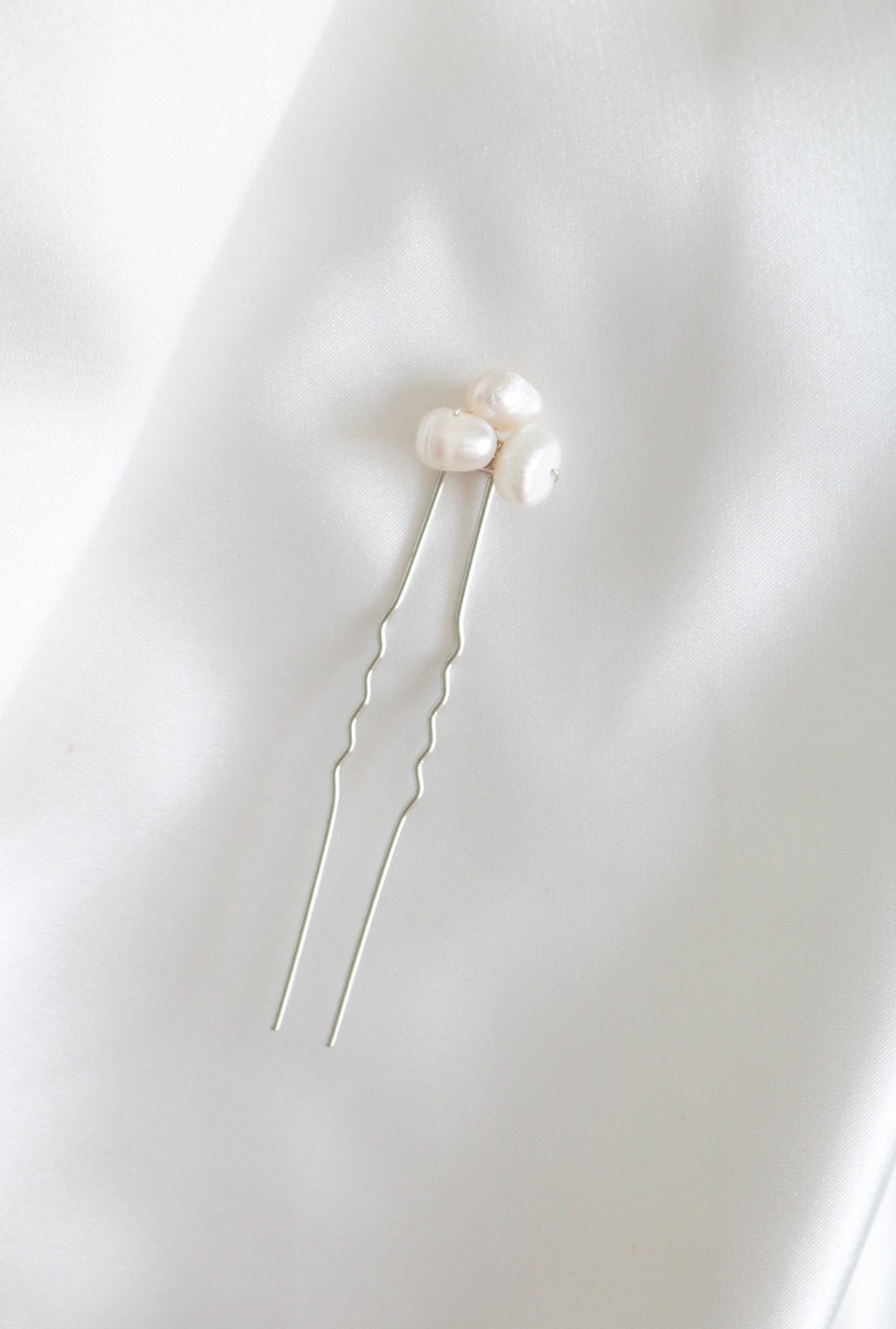 A single silver bridal hairpin with organic freshwater pearls on white background. Handmade pearl accessories for brides by a woman-owned jewelry brand.
