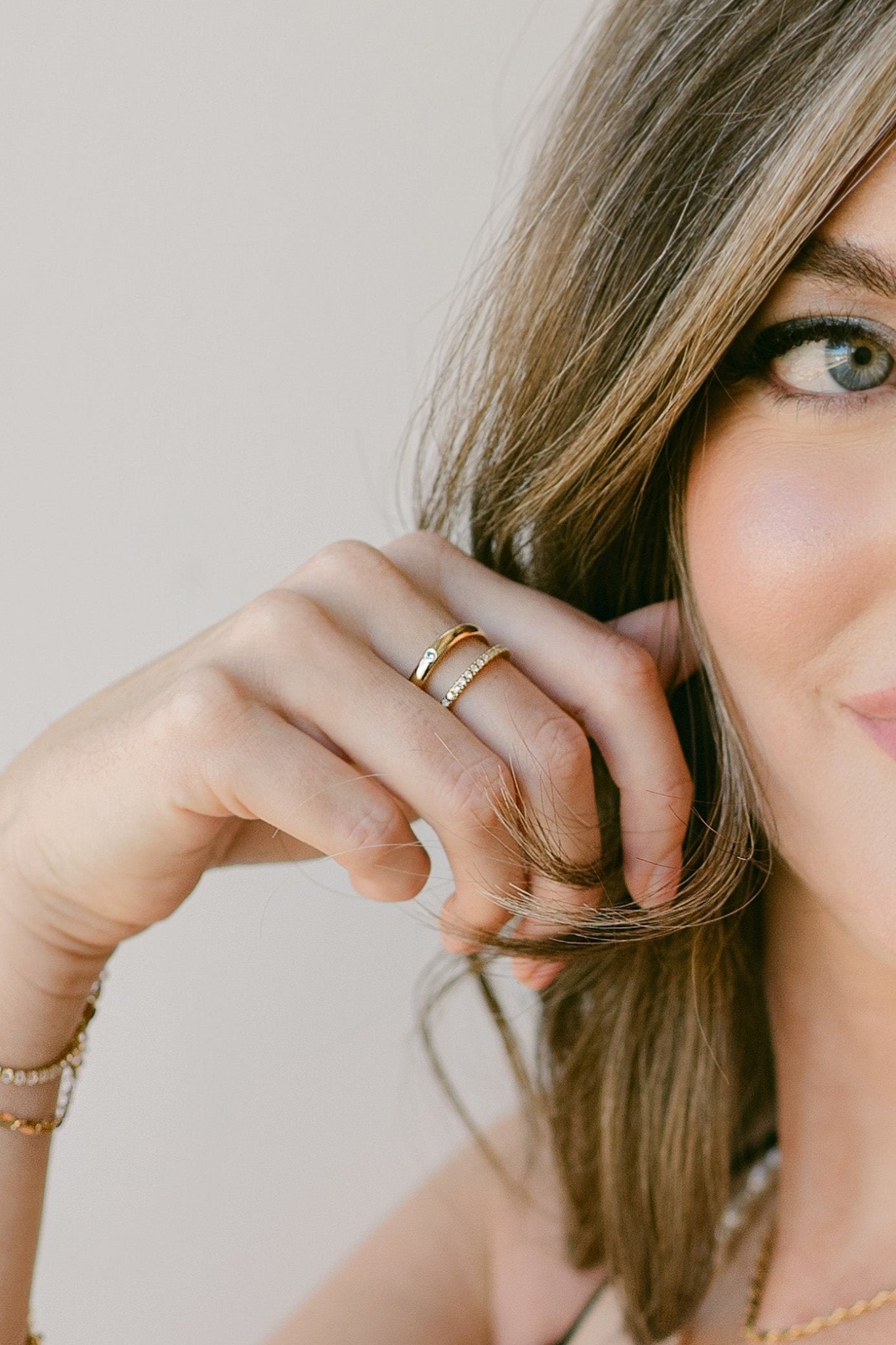 Woman with 2 gold-filled rings on finger; one with multiple cubic zirconia crystals. Canadian jewelry designer. Everyday jewelry.