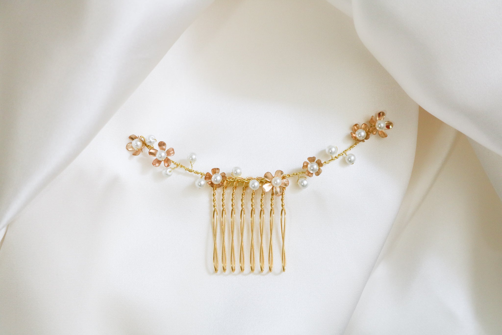 A close up of the Gold Juliette Floral Freshwater Pearl Bridal Comb on a satin white background. Bridal Hair Accessories. Bridal Accessories. Canadian Bridal Accessories. Handmade Canadian Accessories. Canadian handmade Accessories. Canadian weddings. Wedding Canada. Organic pearl accessories. Pearl Bridal Hair Accessories. Pearl Bridal Accessories.