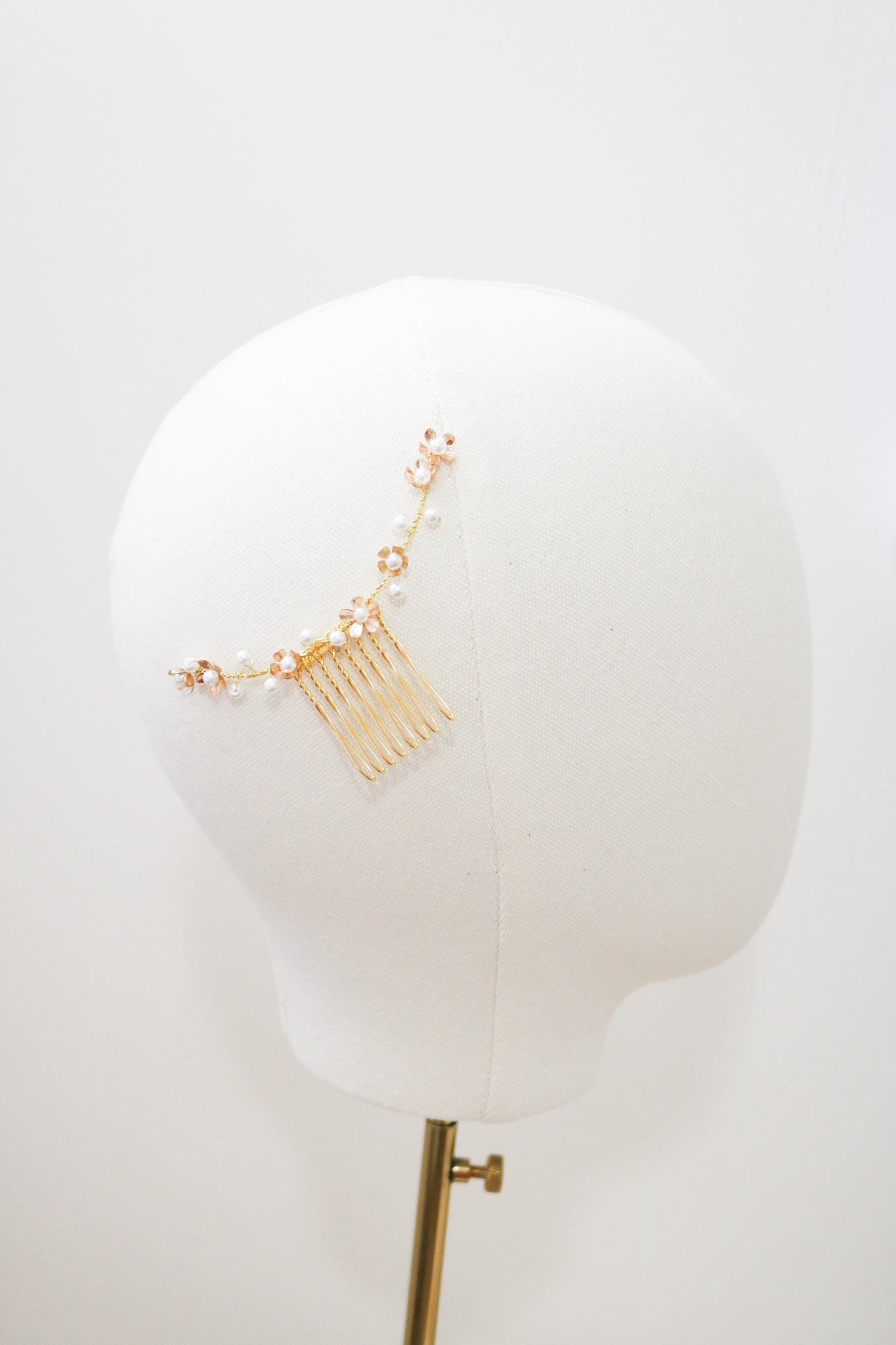 A gold freshwater pearl floral bridal hair comb displayed on the side of a mannequin head. Bridal Hair Accessories. Bridal Accessories. Canadian Bridal Accessories. Handmade Canadian Accessories. Canadian handmade Accessories. Canadian weddings. Wedding Canada. Organic pearl accessories. Pearl Bridal Hair Accessories. Pearl Bridal Accessories.