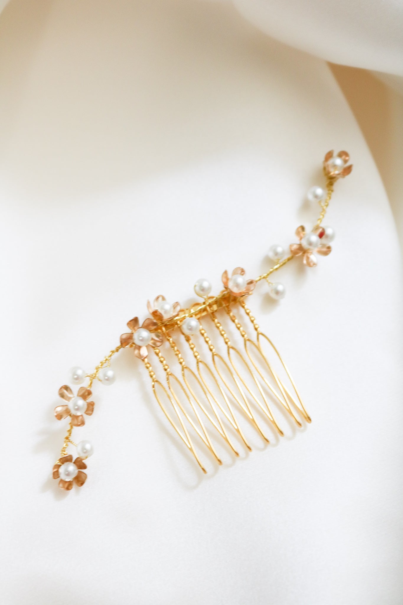 A close up of a shorter gold Swarovski pearl floral bridal hair comb displayed on white background. Handmade bridal hair accessories & Canadian bridal accessories by BIPOC bridal designer