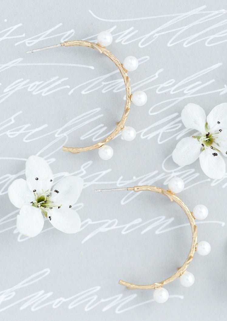A pair of Laurel Freshwater Pearl & Branch Hoops with white flowers on a scrawled background. Gold-filled jewelry Canada. Pearl Jewelry Canada, Pearl Bridal Jewelry Canada. Handmade jewelry Canada.