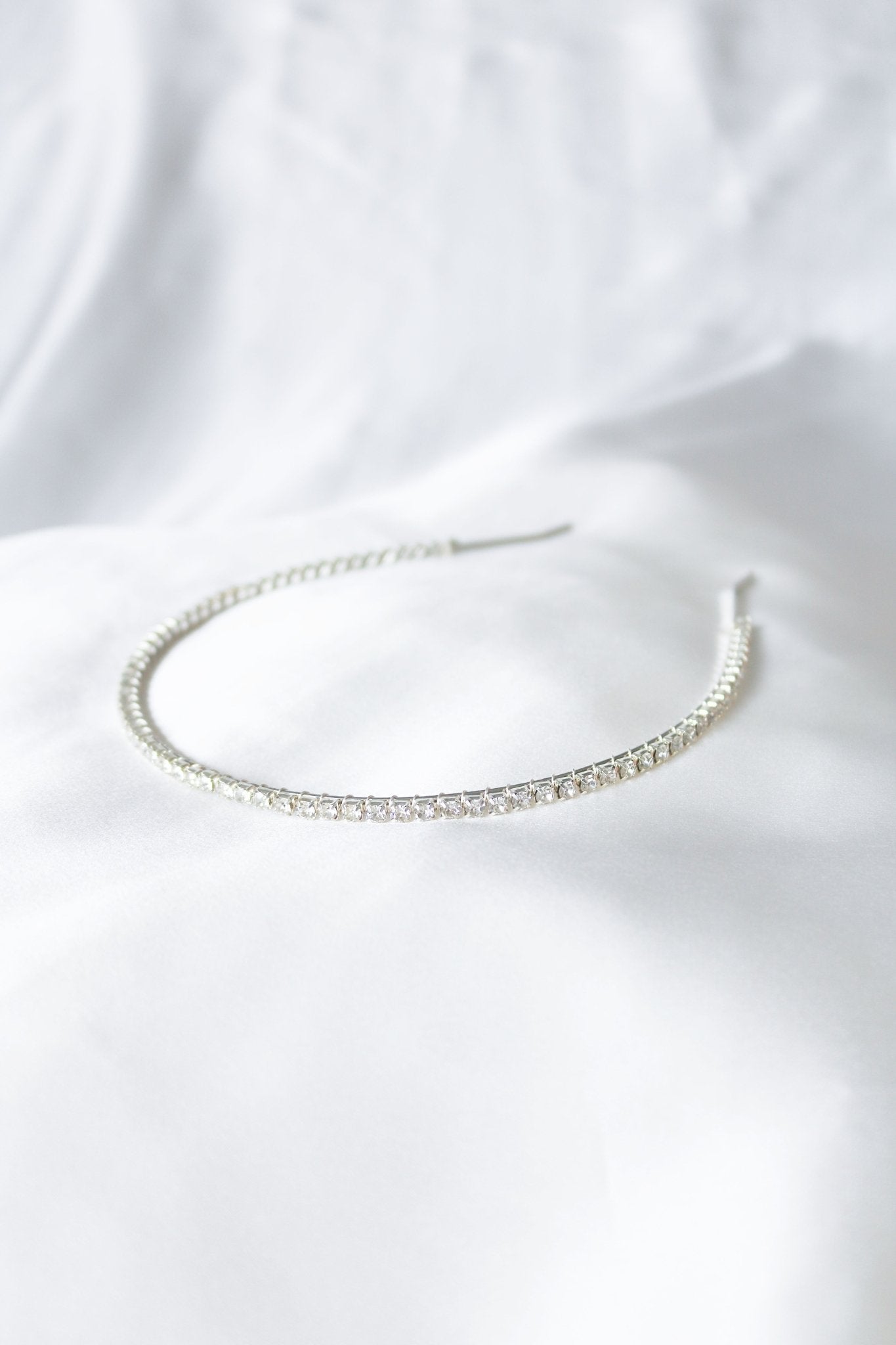 A Silver Crystal Halo headbands on a white satin sheet. Bridal Hair Accessories. Bridal Accessories. Canadian Bridal Accessories. Handmade Canadian Accessories. Canadian handmade Accessories. Canadian weddings. Wedding Canada. Canadian designer. Canadian artist.