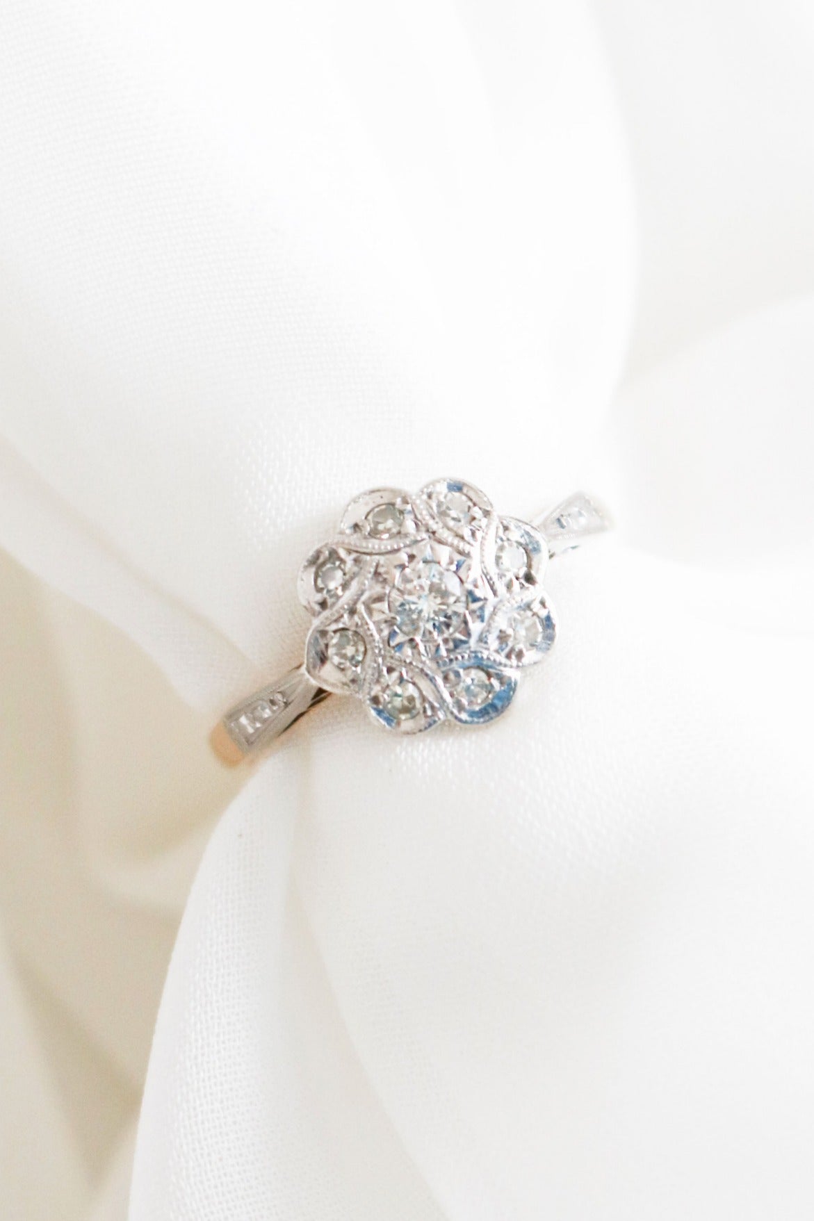 An extreme close up of an 18k Yellow Gold Vintage Engagement Ring with Diamonds in a flower shape displayed around white tulle fabric. Canadian vintage engagement rings. Bridal jewelry Canada. Vintage engagement rings Canada. Canadian weddings. Wedding Canada. Woman-owned Canadian jewelry brand. Canadian jewelry business. Small Canadian jewelry brands.