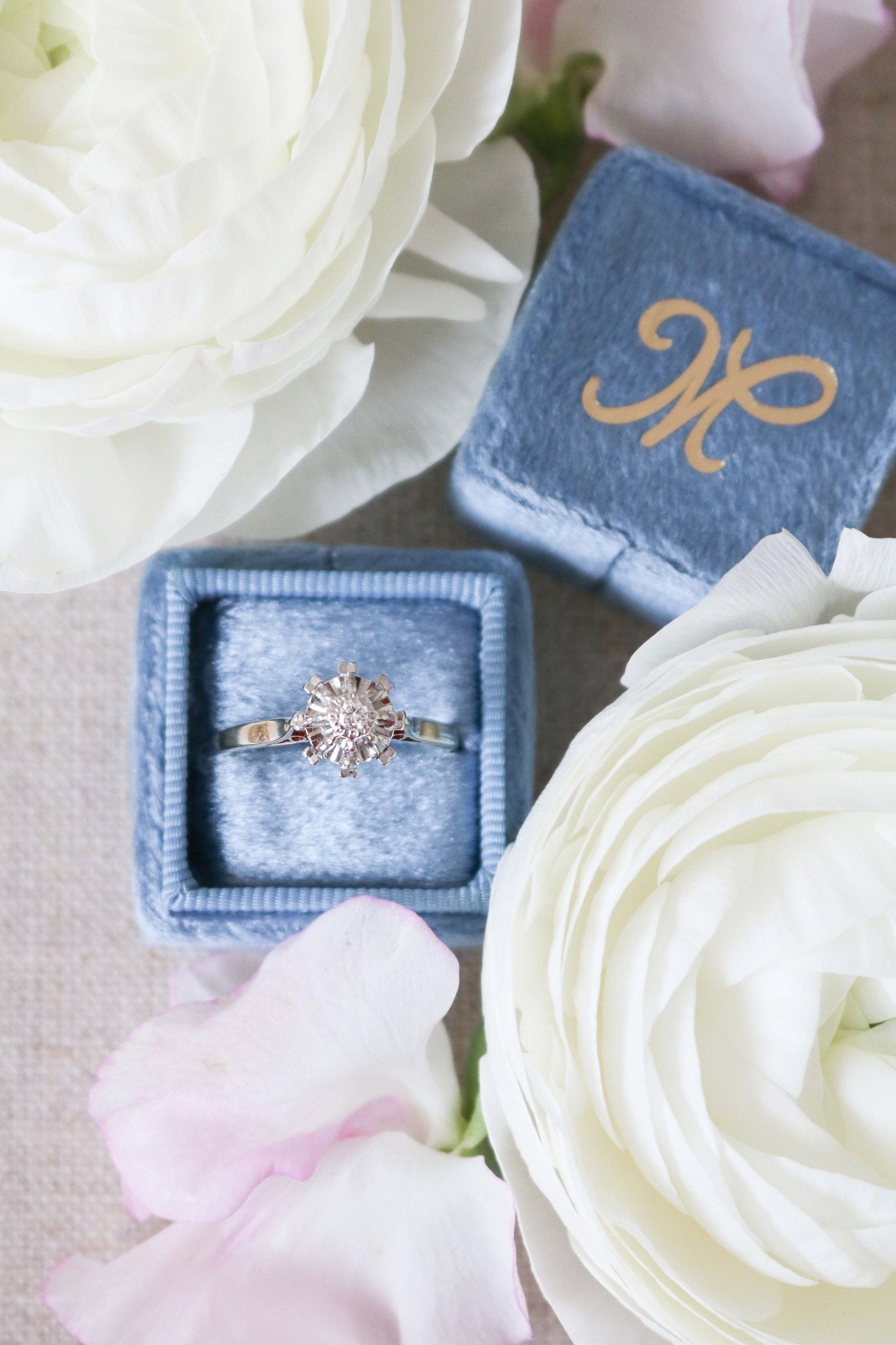 The Liona Floral Vintage Engagement Ring in 14ct Gold, Art Deco Style c.1920s. Ring sitting in a blue ring box surrounded by white roses. Antique Engagement Rings Canada. Canadian vintage engagement rings. Vintage engagement rings Canada. Bridal jewelry Canada.