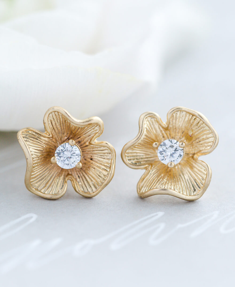 A pair of gold flower studs with cubic zirconia middles.