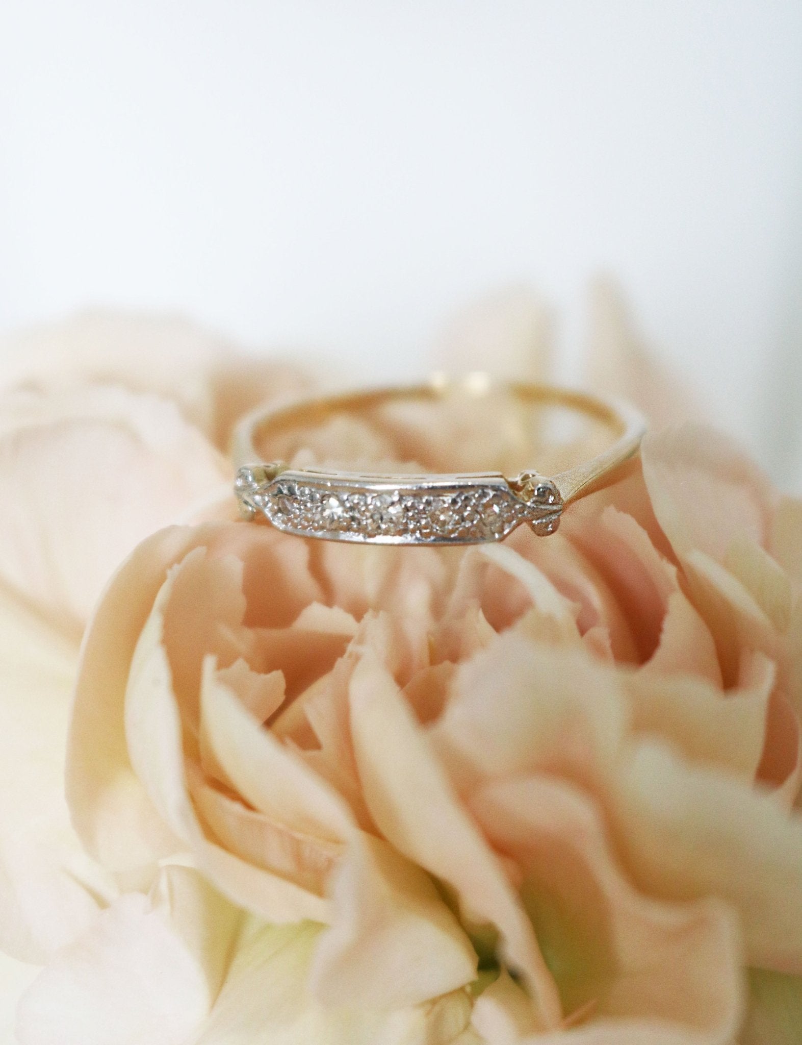 A Vintage Diamond Engagement Ring/Wedding Band in 18k Yellow and White Gold lays atop a yellow flower. Canadian vintage engagement rings. Bridal jewelry Canada. Canadian weddings. Wedding Canada. Small Canadian jewelry brands. Canadian jewelry brands. Affordable Canadian jewelry brands.