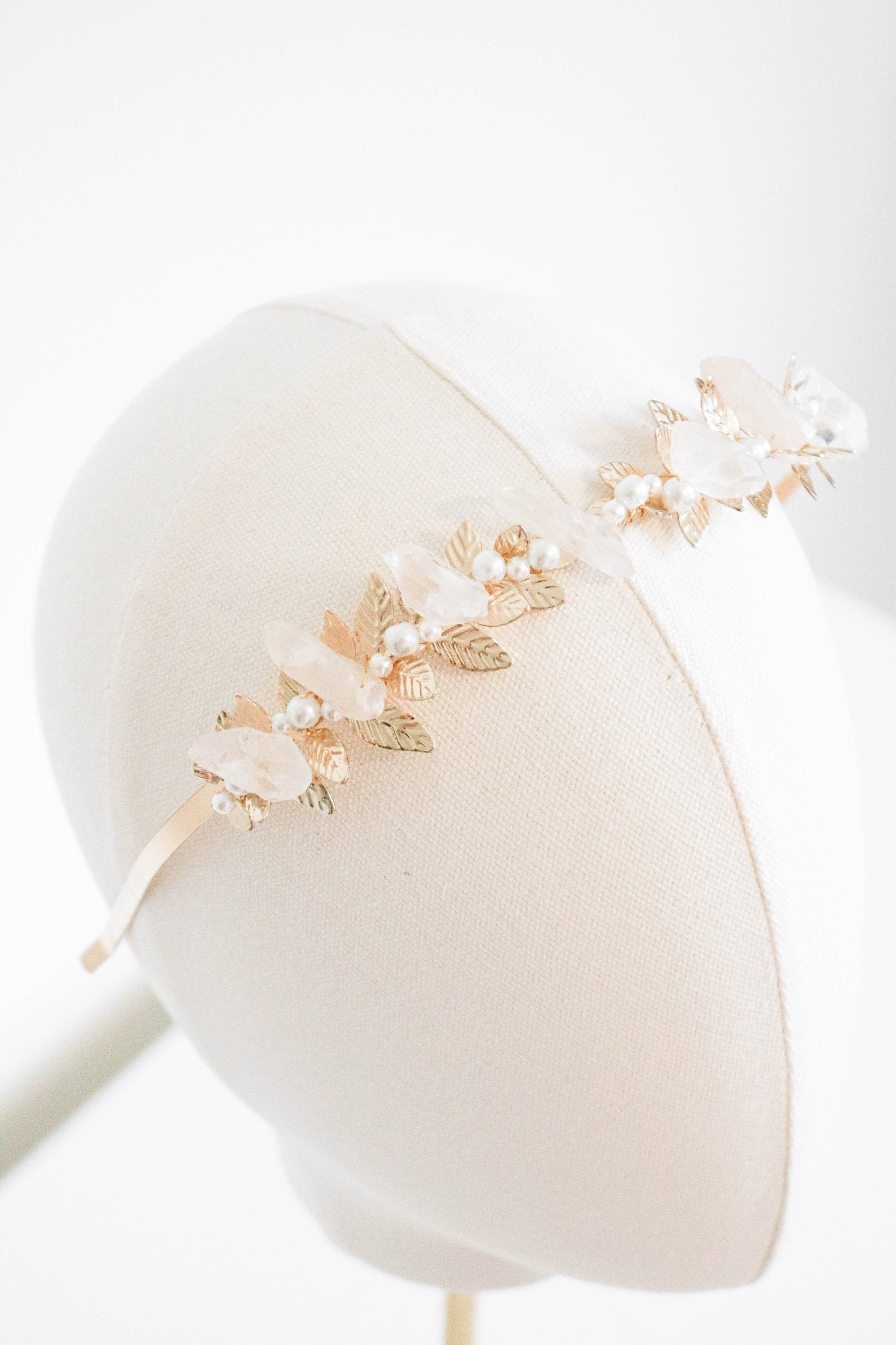 A gold laurel bridal headband with quartz crystals and freshwater pearls displayed on a head bust. Bridal hair pieces & bridal hair accessories handmade by BIPOC jewelry designer